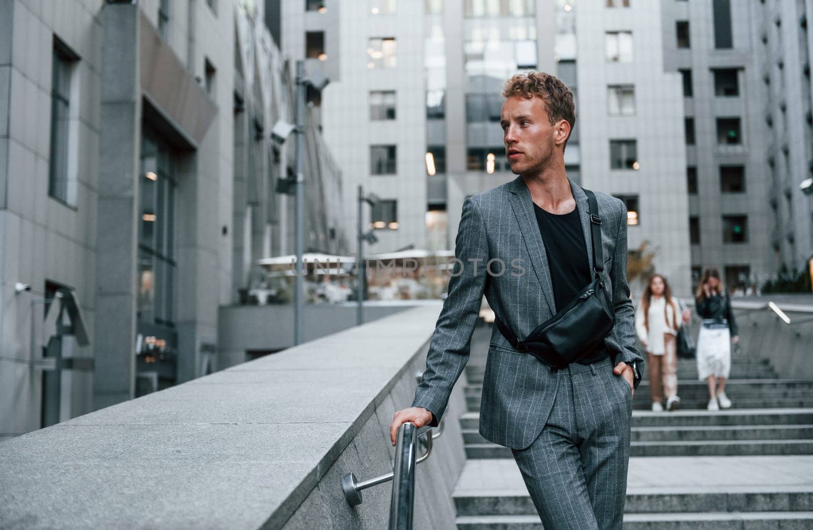 Young elegant man in good clothes is outdoors in the city at daytime.