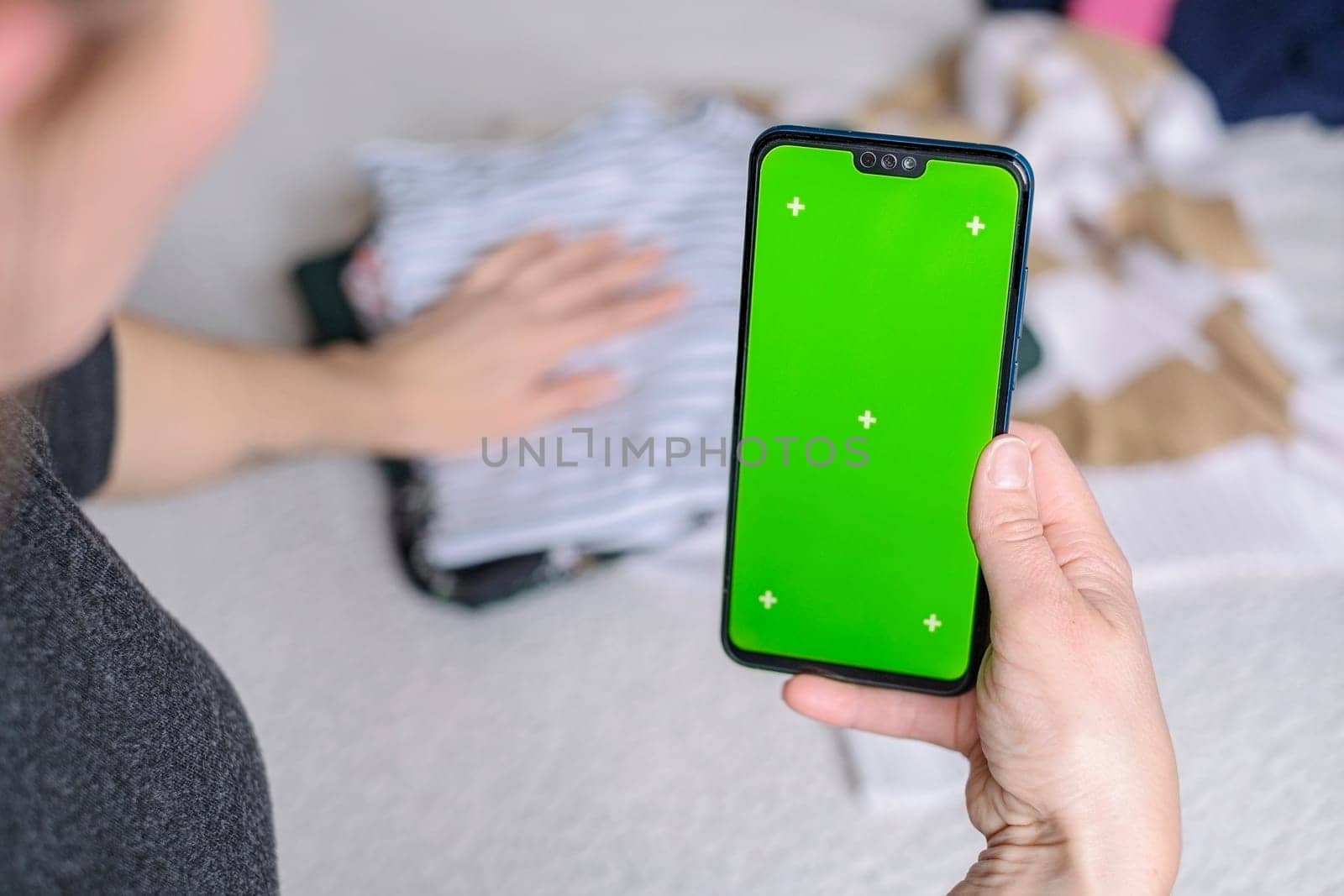 Smartphone with Chroma Key Green Screen close-up. Buying Used Second Hand recycled clothes. Home sale. Recycling Eco New Life, European Store.