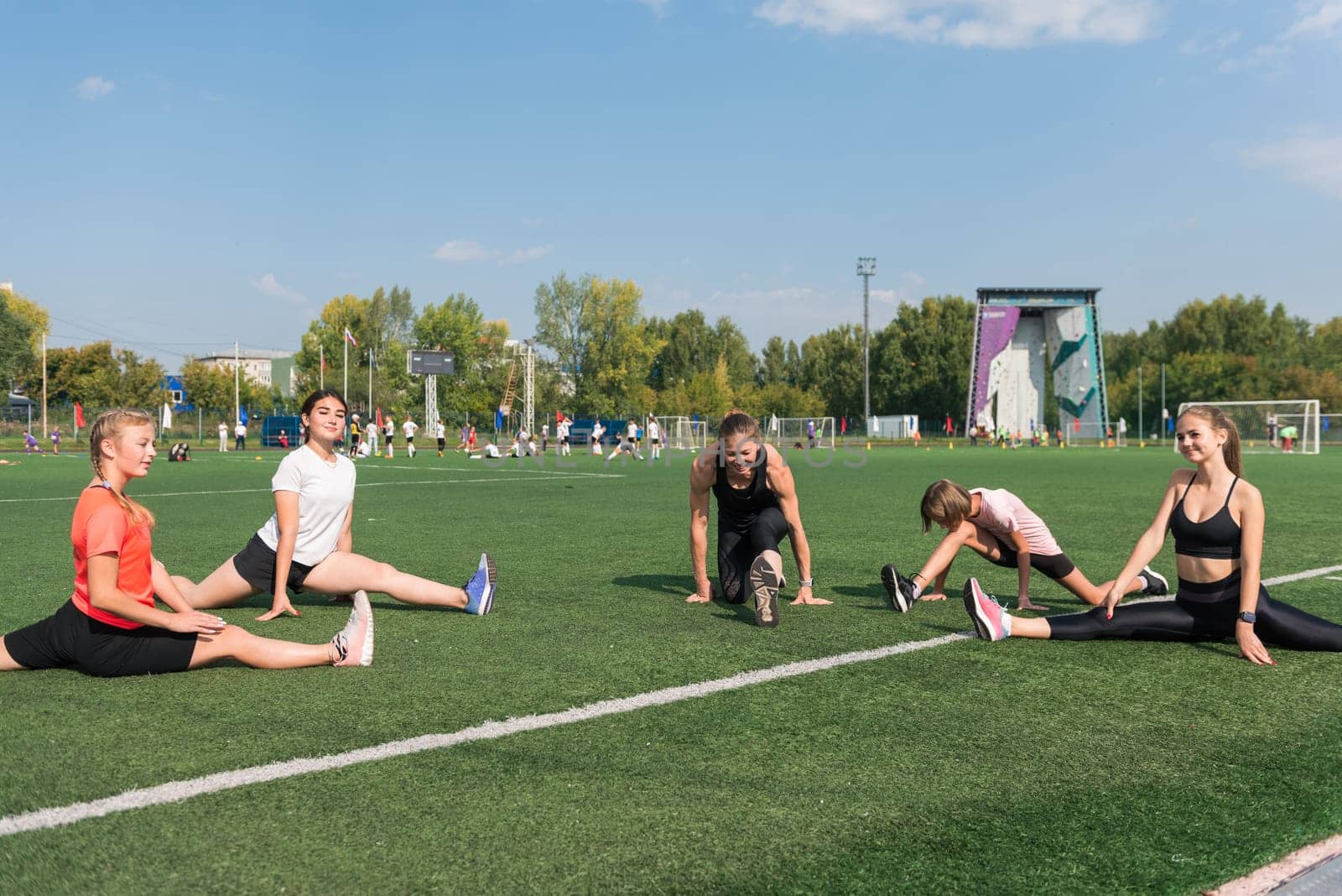 Female coach and group of children conducts a training session at the stadium outdoors