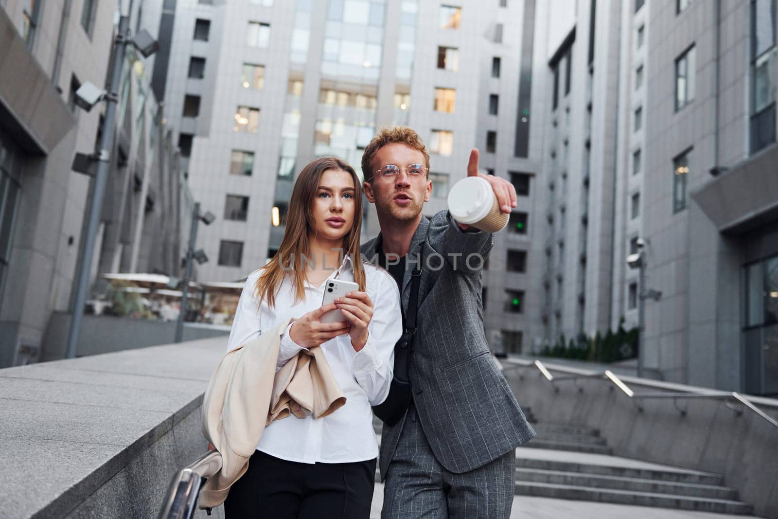 With phone and drink. Woman and man in the town at daytime. Well dressed people by Standret