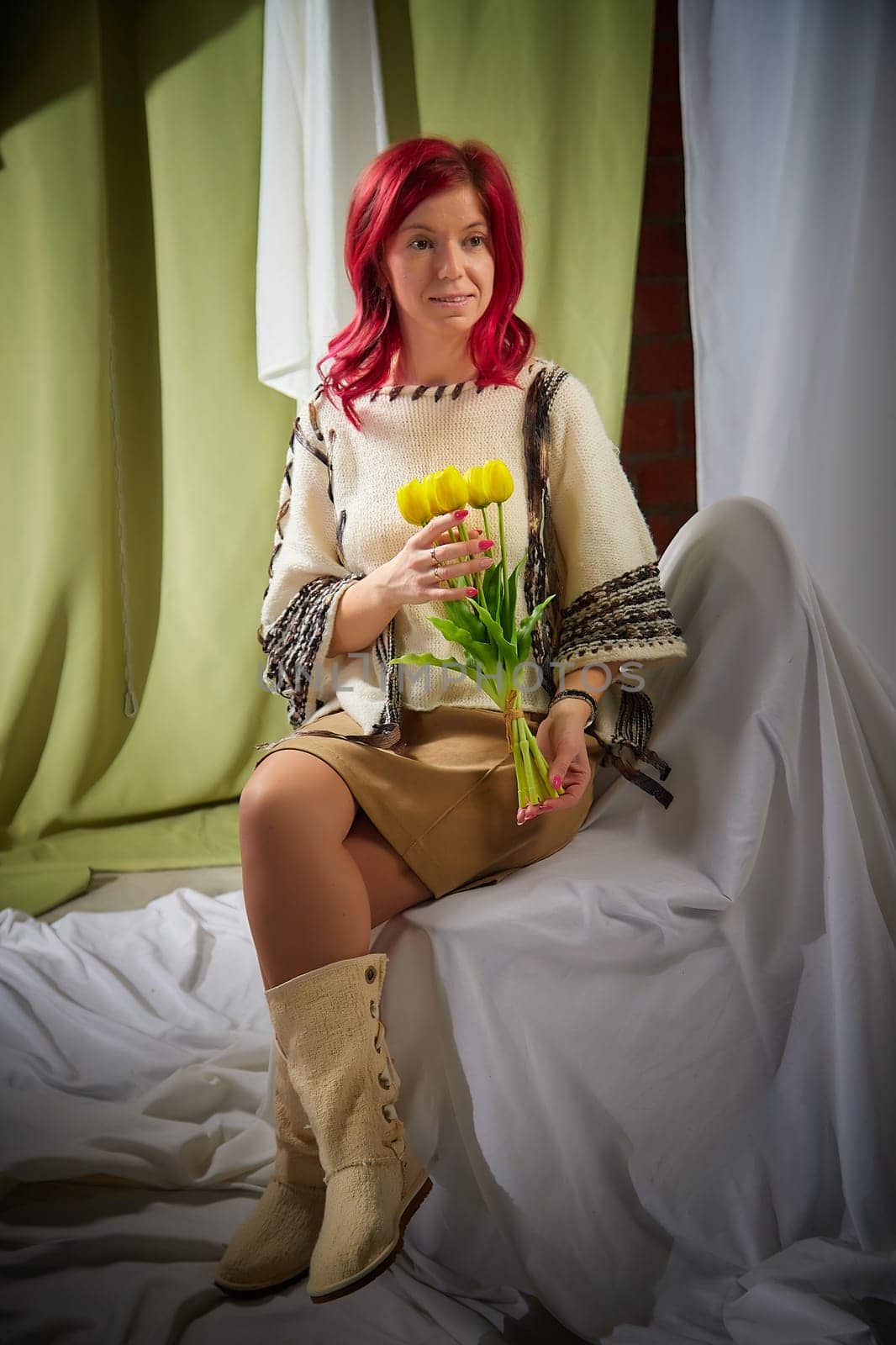 Beautiful woman with red hair on a light background holds tulips. Inernational woman's day 8 March by keleny