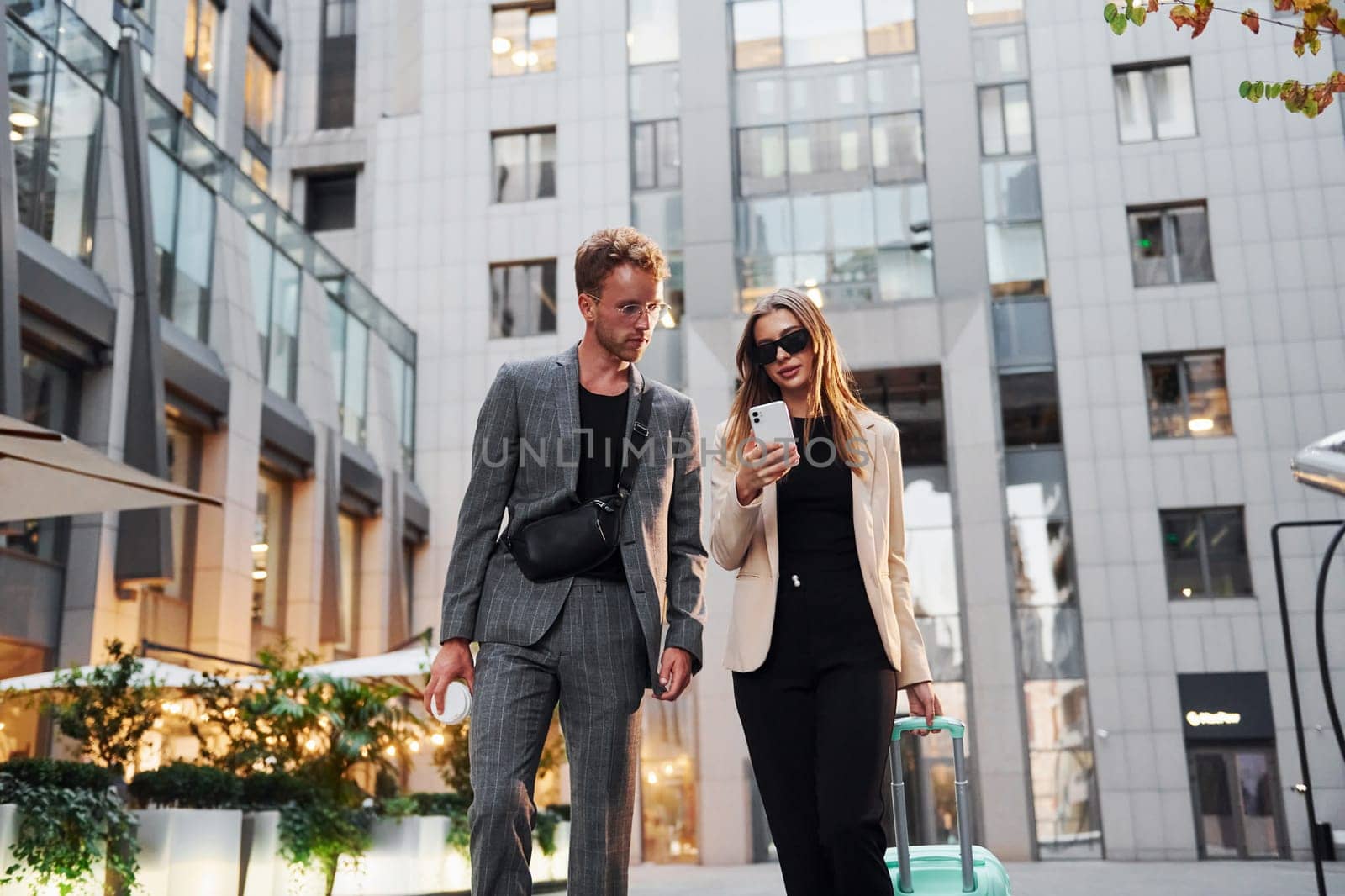 Beautiful business buildings. Woman and man in the town at daytime. Well dressed people.