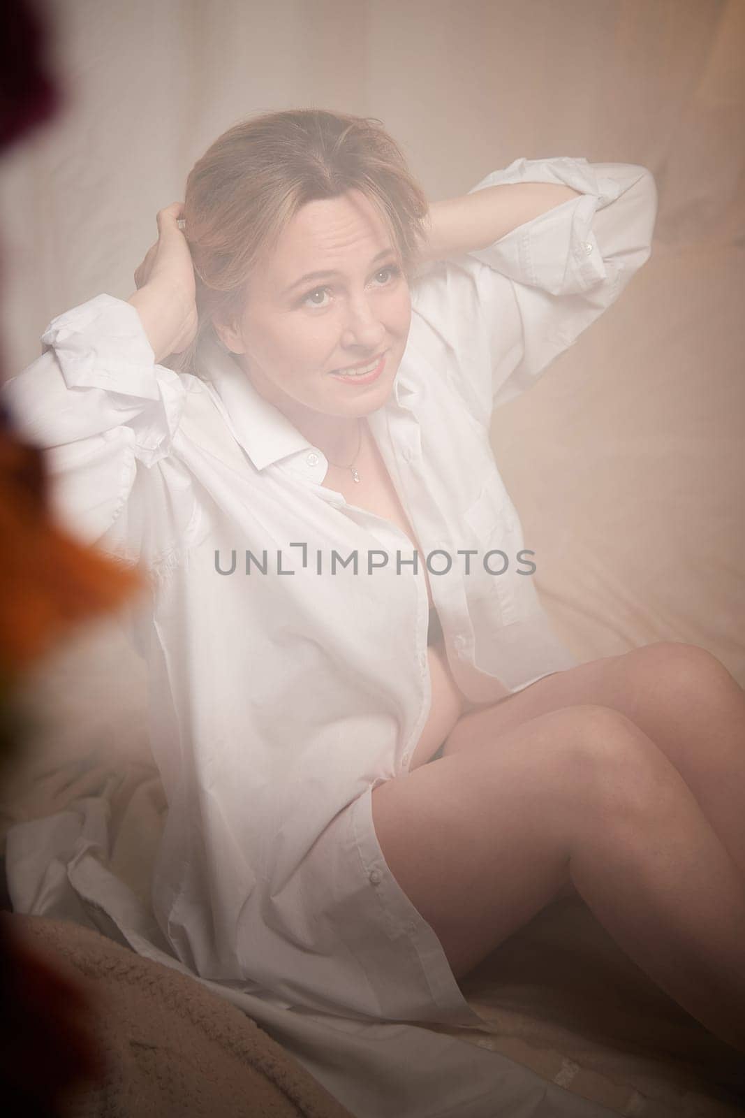 Portrait of sexual body positive adult lady woman in intimate in tender space indoors in a bedroom. Plump girl poses in black underwear and white shirt during boudoir style photo shoot