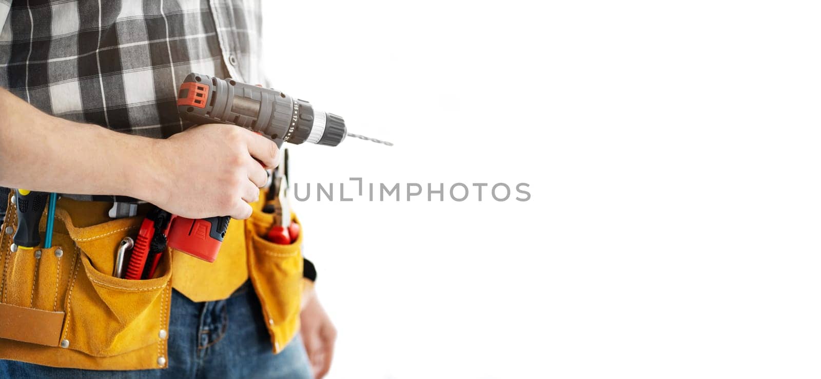 Man wearing mounting belt with tools for repair holding drill in hands isolated on white background. Professional equipment of handyman