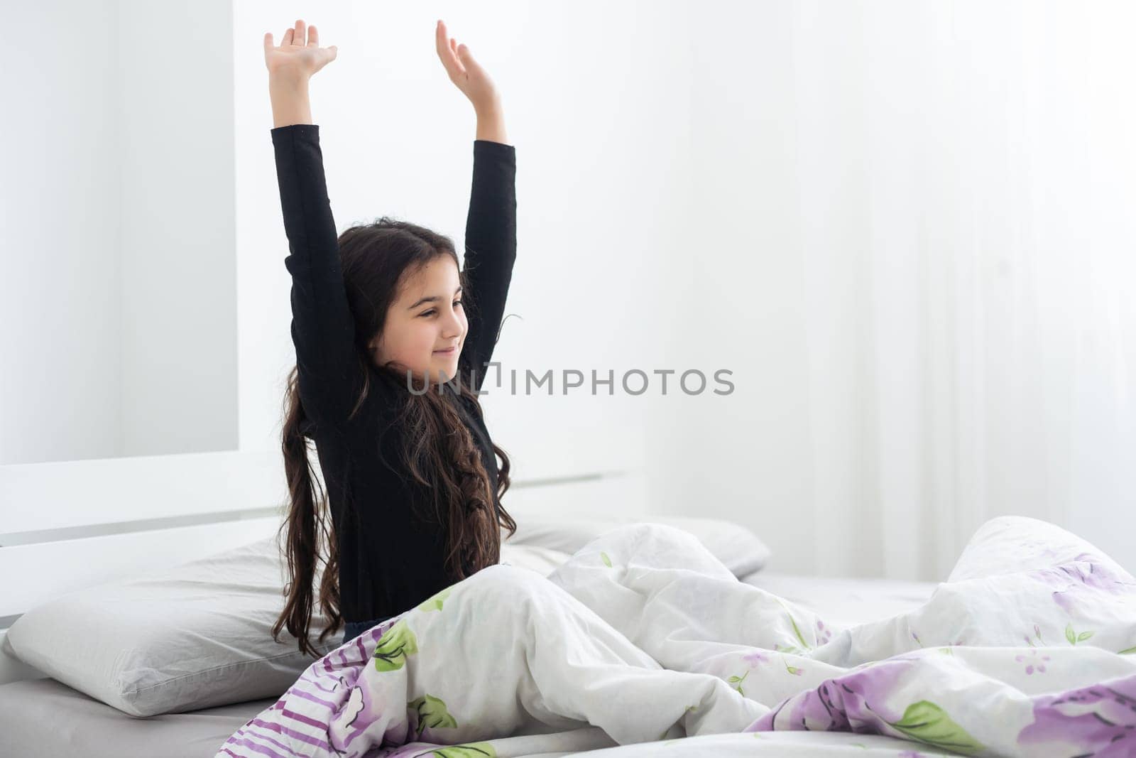 Cute teenage girl stretching on the bed in her room having fun