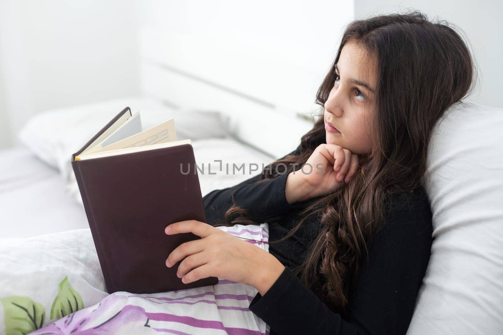 teenage girl with a book in bed.