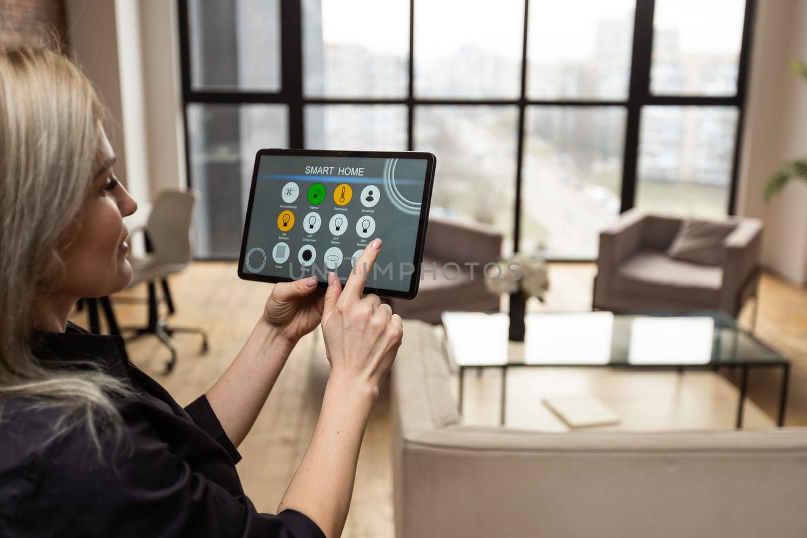 young woman using smart home app to control light turning on with tablet pc.