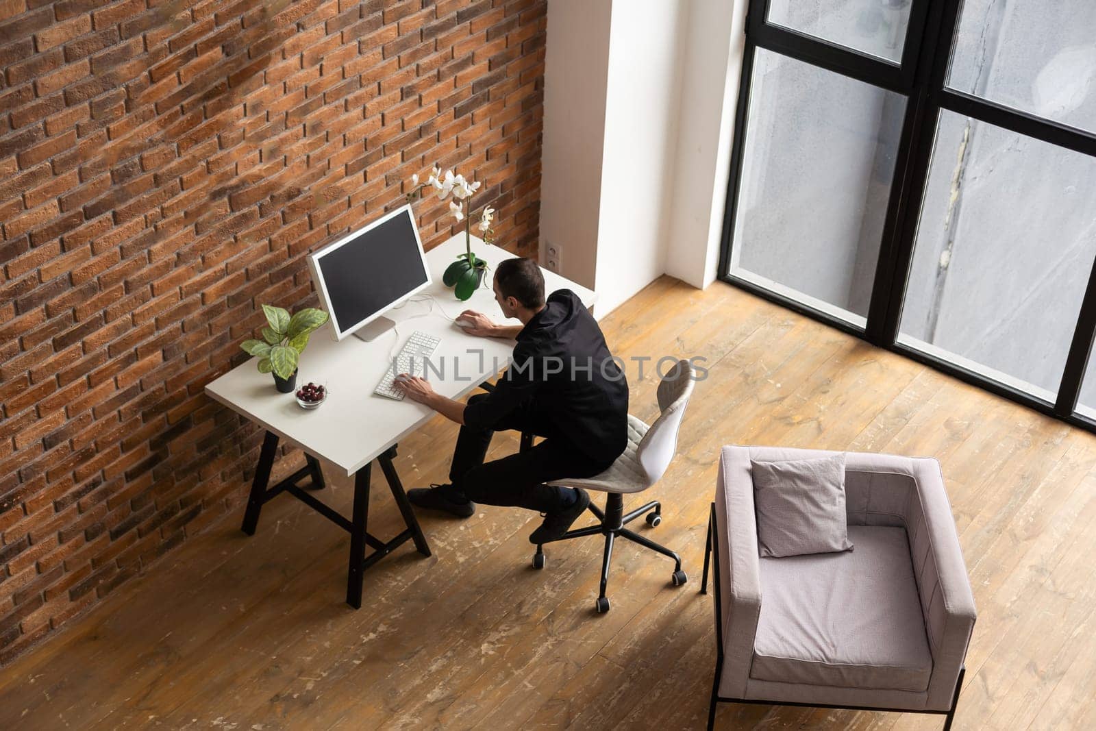 Focused young man using laptop, typing on keyboard, writing email or message, chatting, shopping, successful freelancer working online on computer