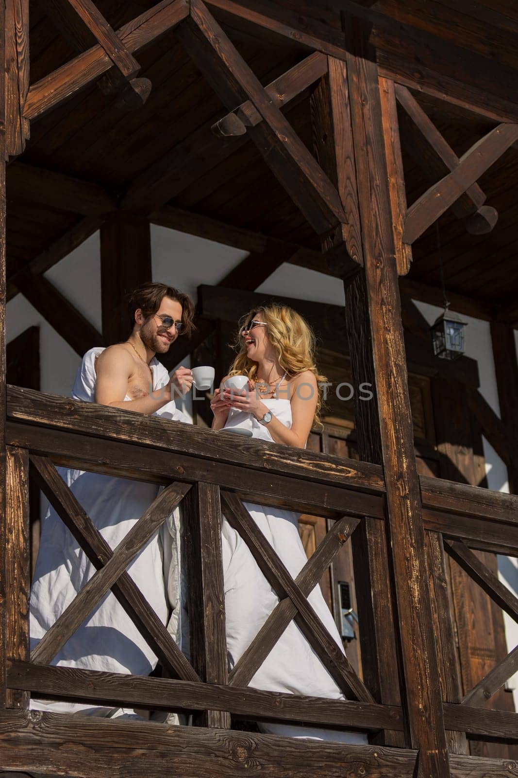 couple wrapped in blankets drinking coffee on the balcony