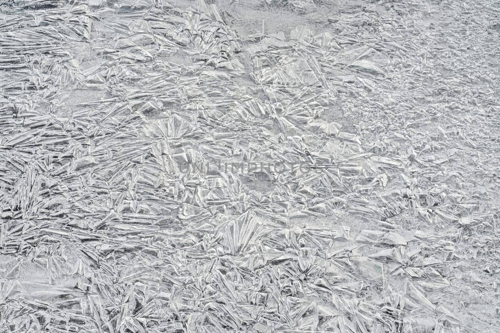 Ice on frozen river, trapped bubbles forming crystal like structures, closeup macro detail from above - abstract winter background.