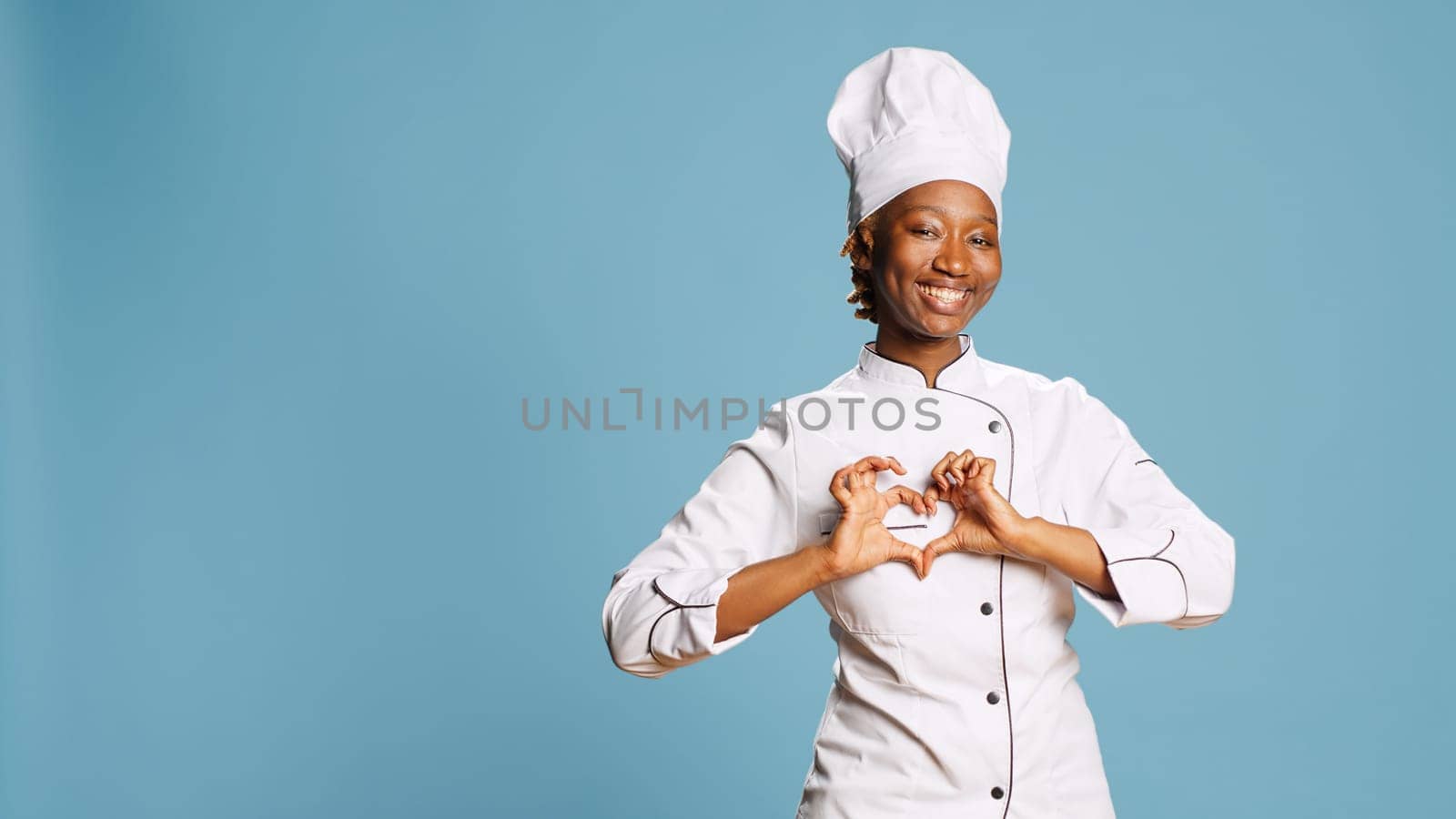 Female cook showing heart shaped symbol on camera by DCStudio