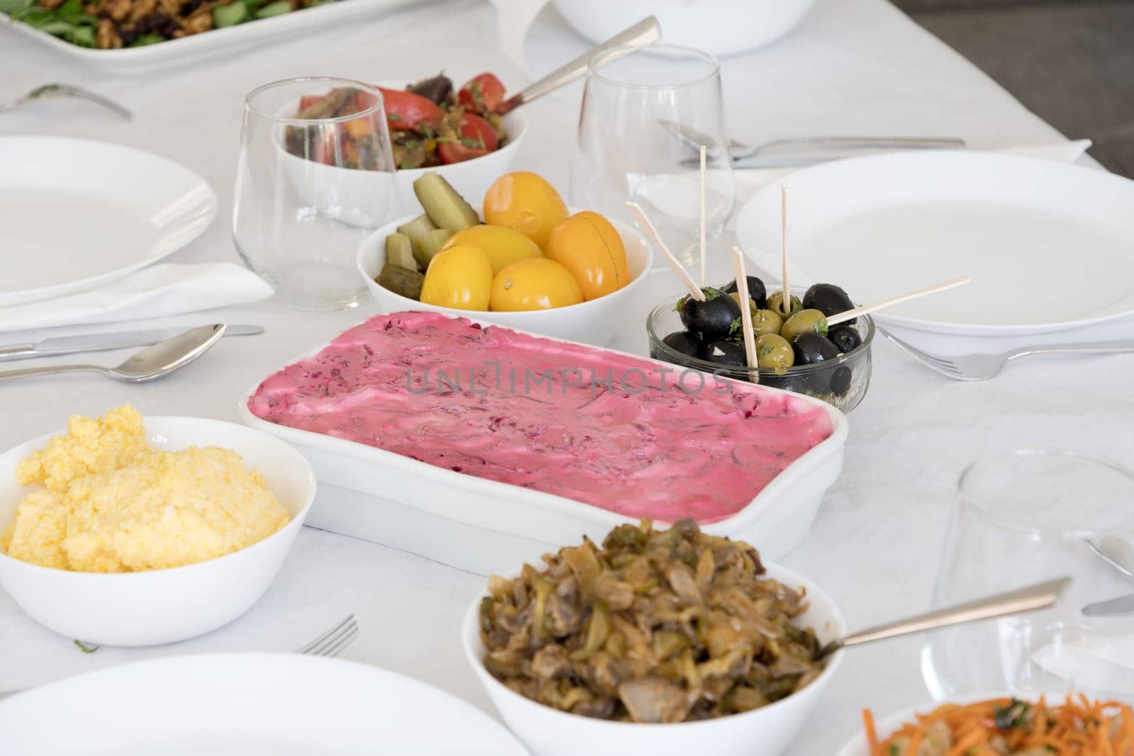 Traditional Russian holiday salad Herring under a fur coat in salad bowl on the table between other tasty appetizers for the holiday, High quality photo