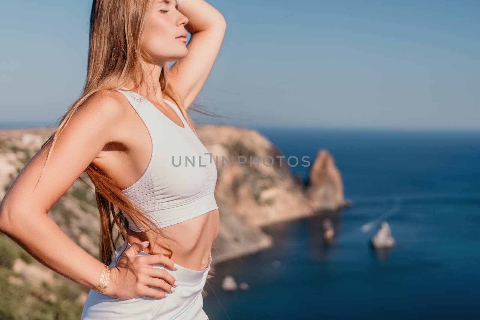 Woman travel sea. Young Happy woman in a long red dress posing on a beach near the sea on background of volcanic rocks, like in Iceland, sharing travel adventure journey