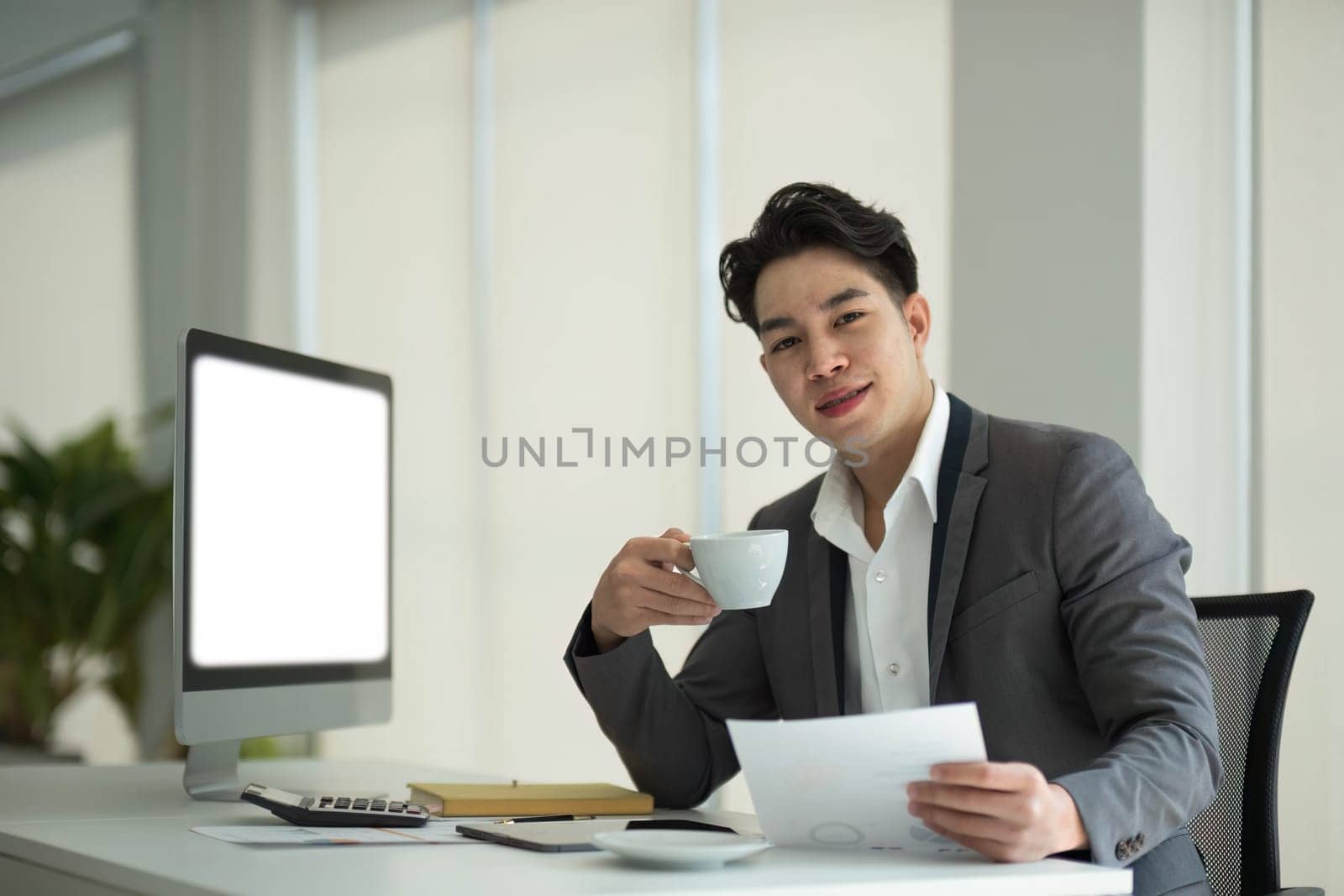 Business man working analyst of work on lnotebook pc while sitting at wooden table. Business man analyze stock report on notebook pc screen by wichayada