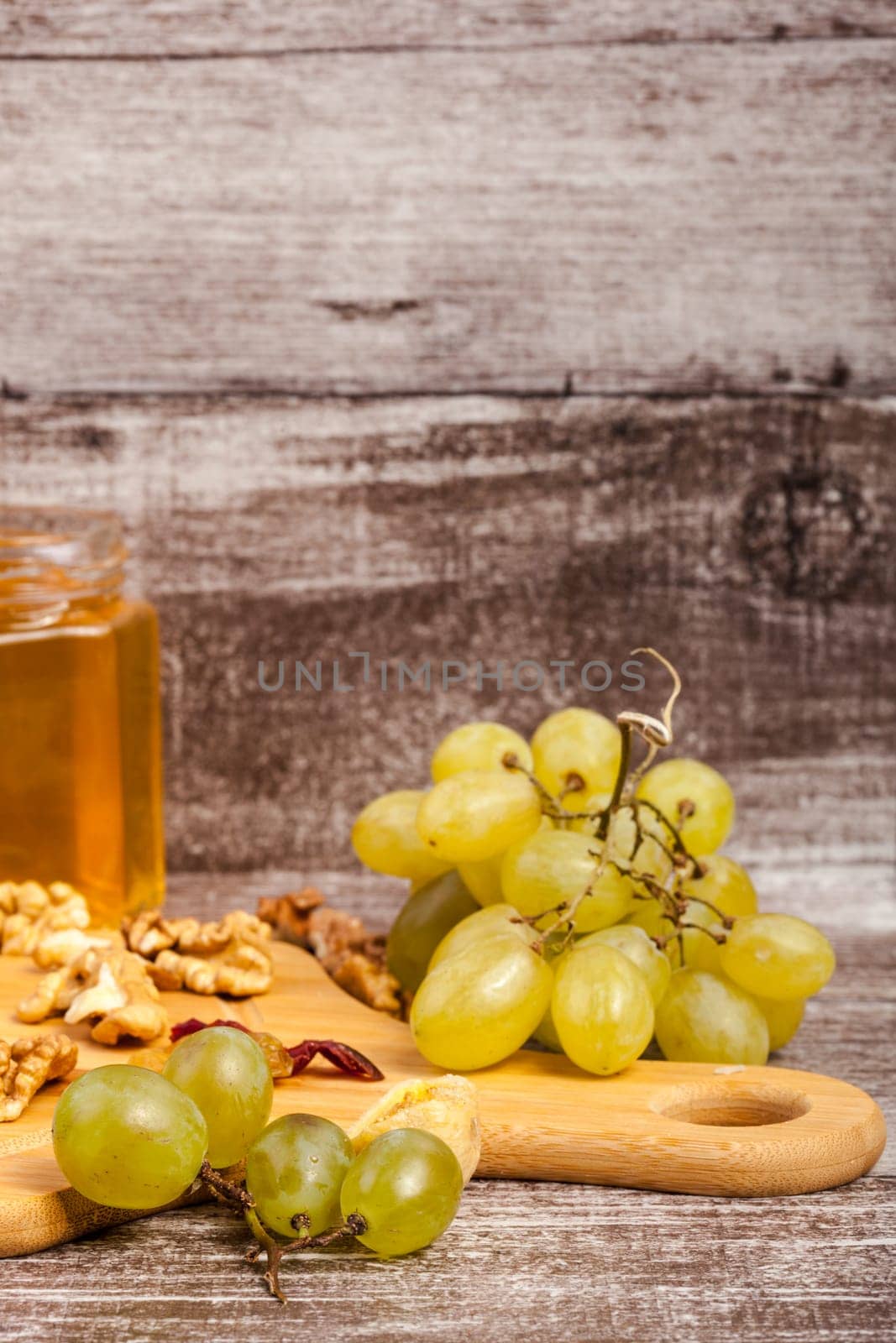 Nuts, honey and grape on wooden background by DCStudio
