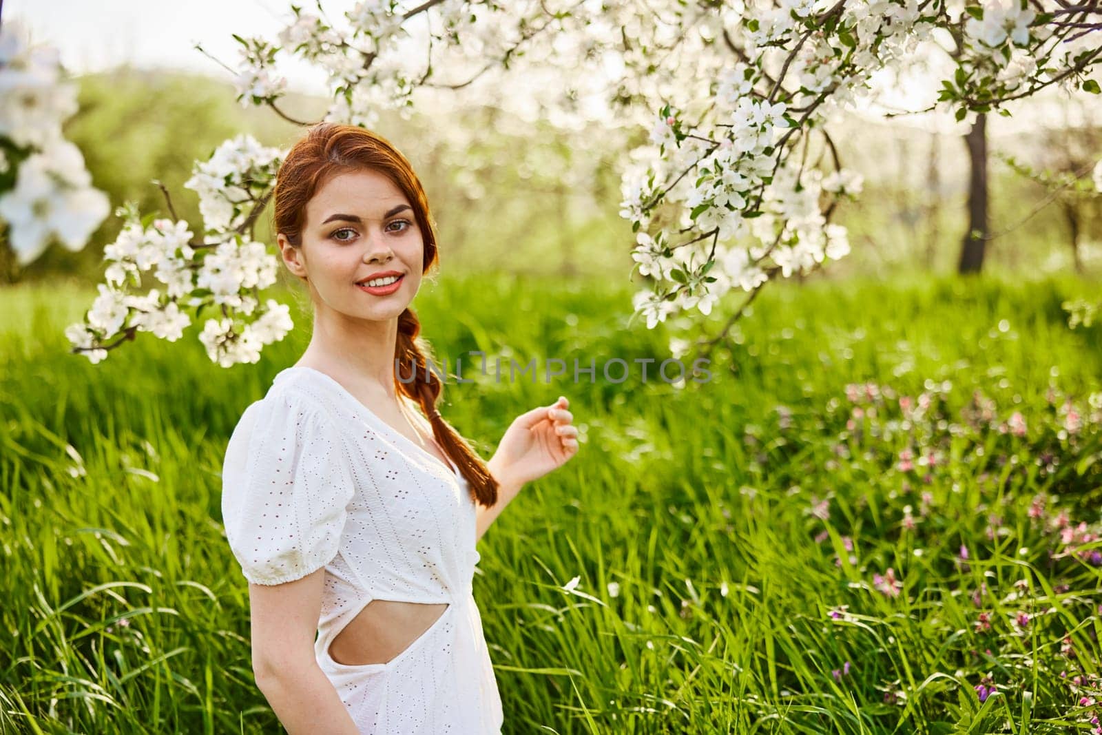 a young woman in a light summer dress is resting sitting under a flowering tree. High quality photo