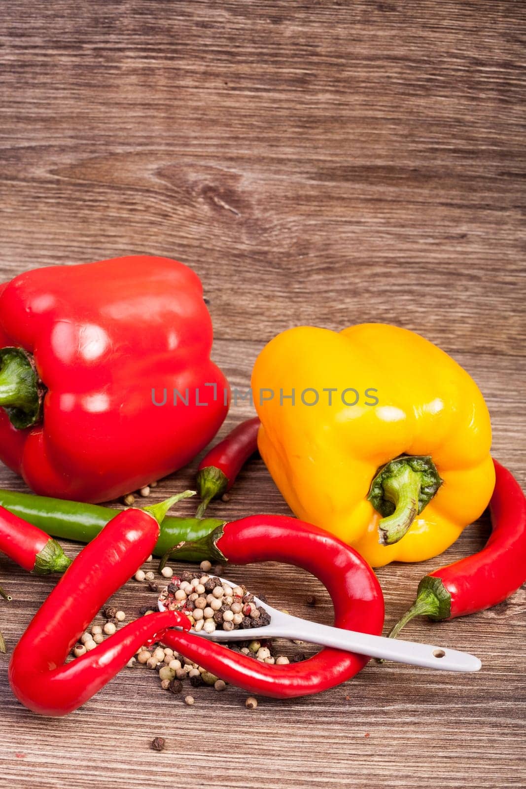Sweet and hot pepper on wooden background by DCStudio