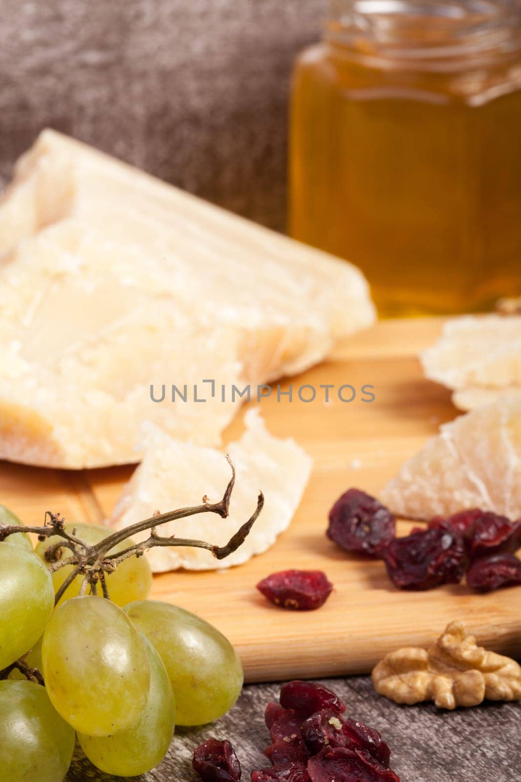 Cheese, grape, nuts and honey on wooden background in studio photo