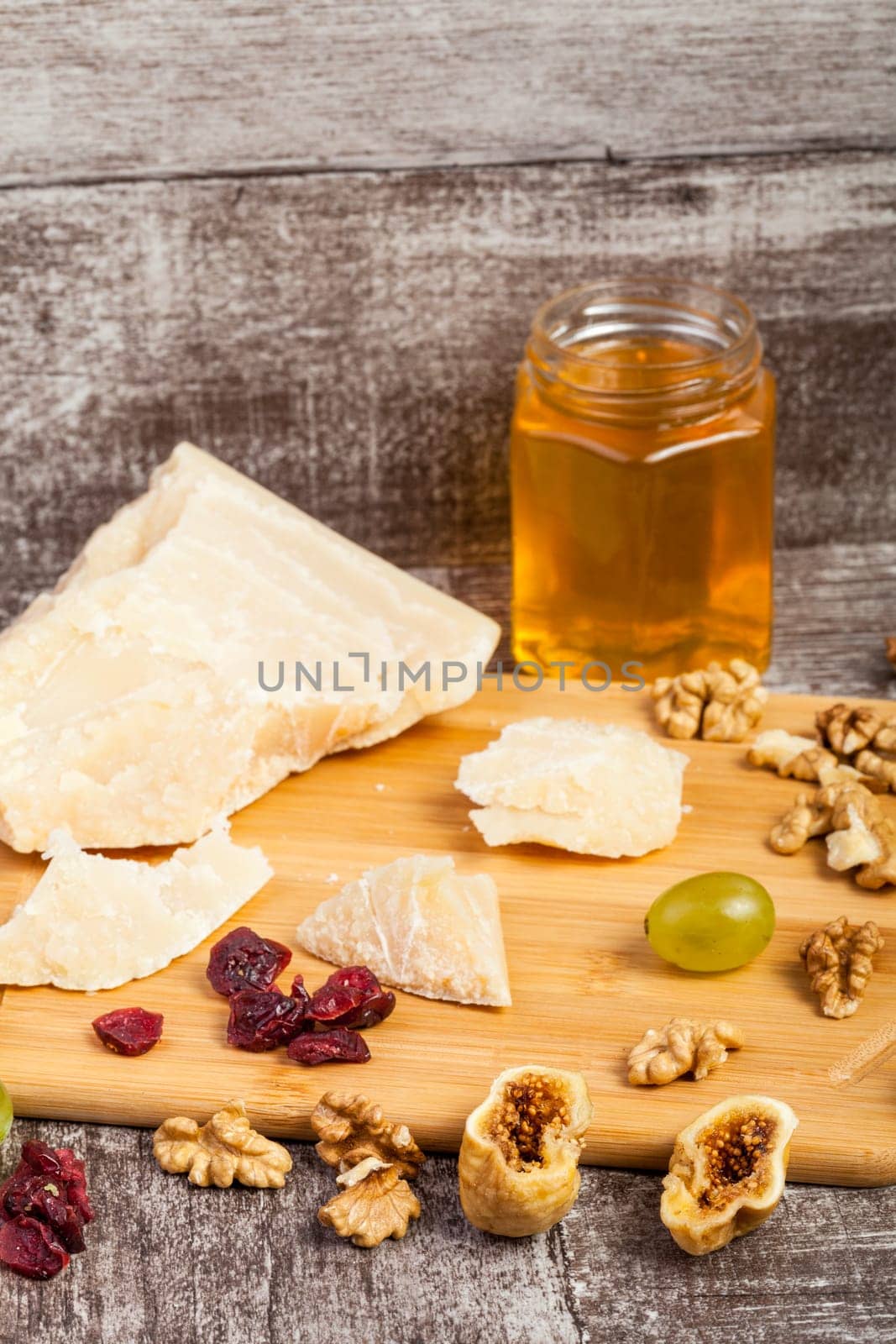 Fruits, grapes, cheese and honey on wooden background by DCStudio
