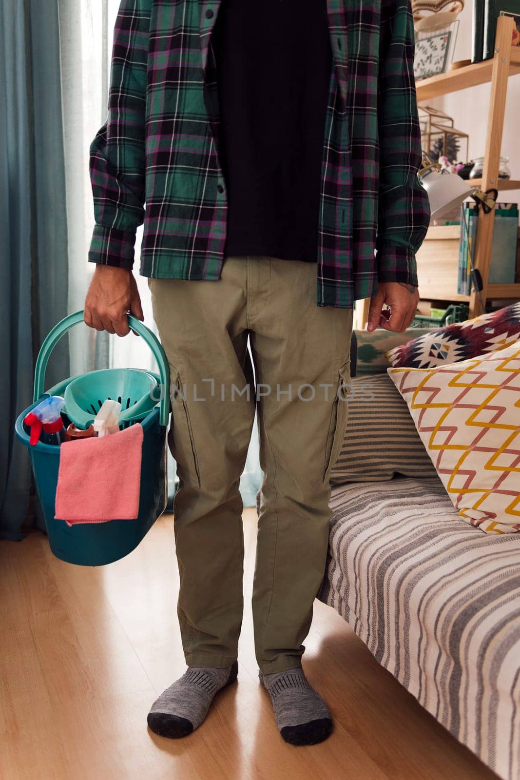 unrecognizable man holding a bucket with cleaning products and a rag, home cleaning concept