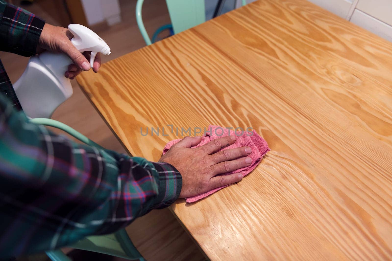 closeup of the hands of a person cleaning a wooden table with a rag and a spray, home cleaning concept, copy space for text