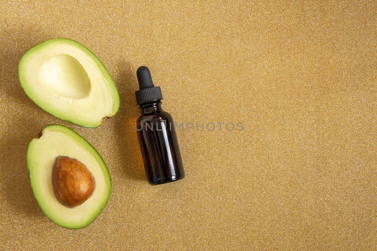 Cosmetic bottle with avocado oil on a golden shiny glitter background. Advertising mock up, copy space. by Ri6ka