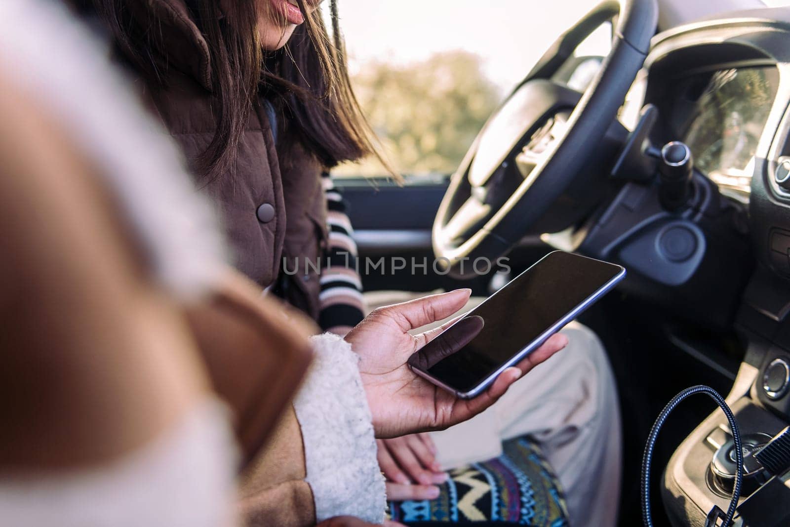 close up of the hands of two young women using gps at phone on a road trip, concept of adventure and travel with best friend