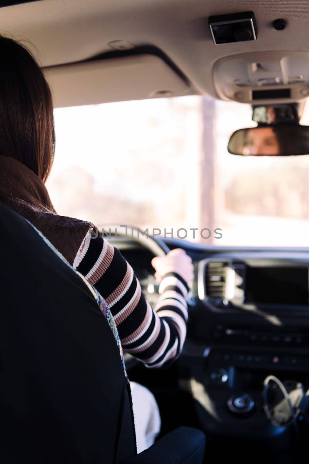 rear view of a young woman driving her camper van to new horizons, concept of road trip and nomad lifestyle, copy space for text