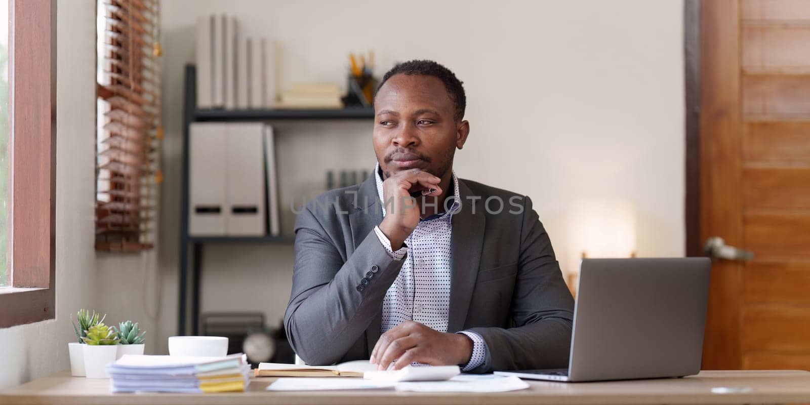 Tired American African business man in stress works with many paperwork document. migraine attack. Freelance, work from home.