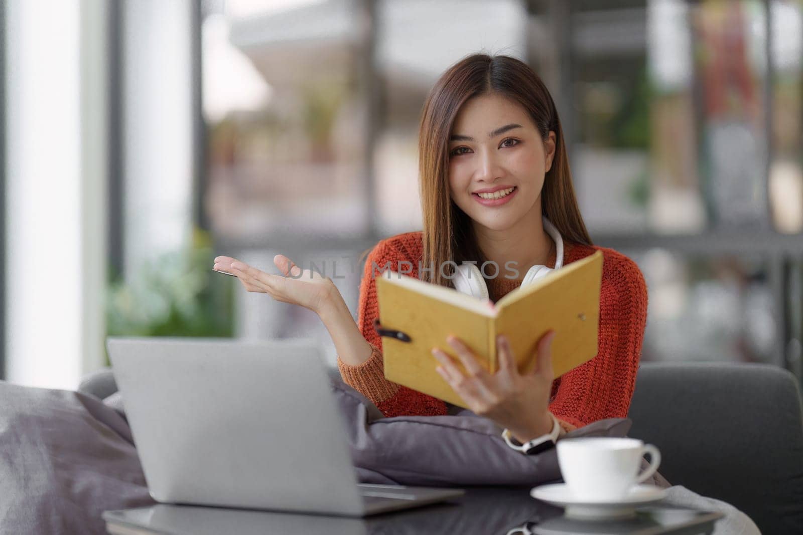 Beautiful Asian Woman smile and relaxing at home and using laptop computer sitting on cozy sofa by itchaznong