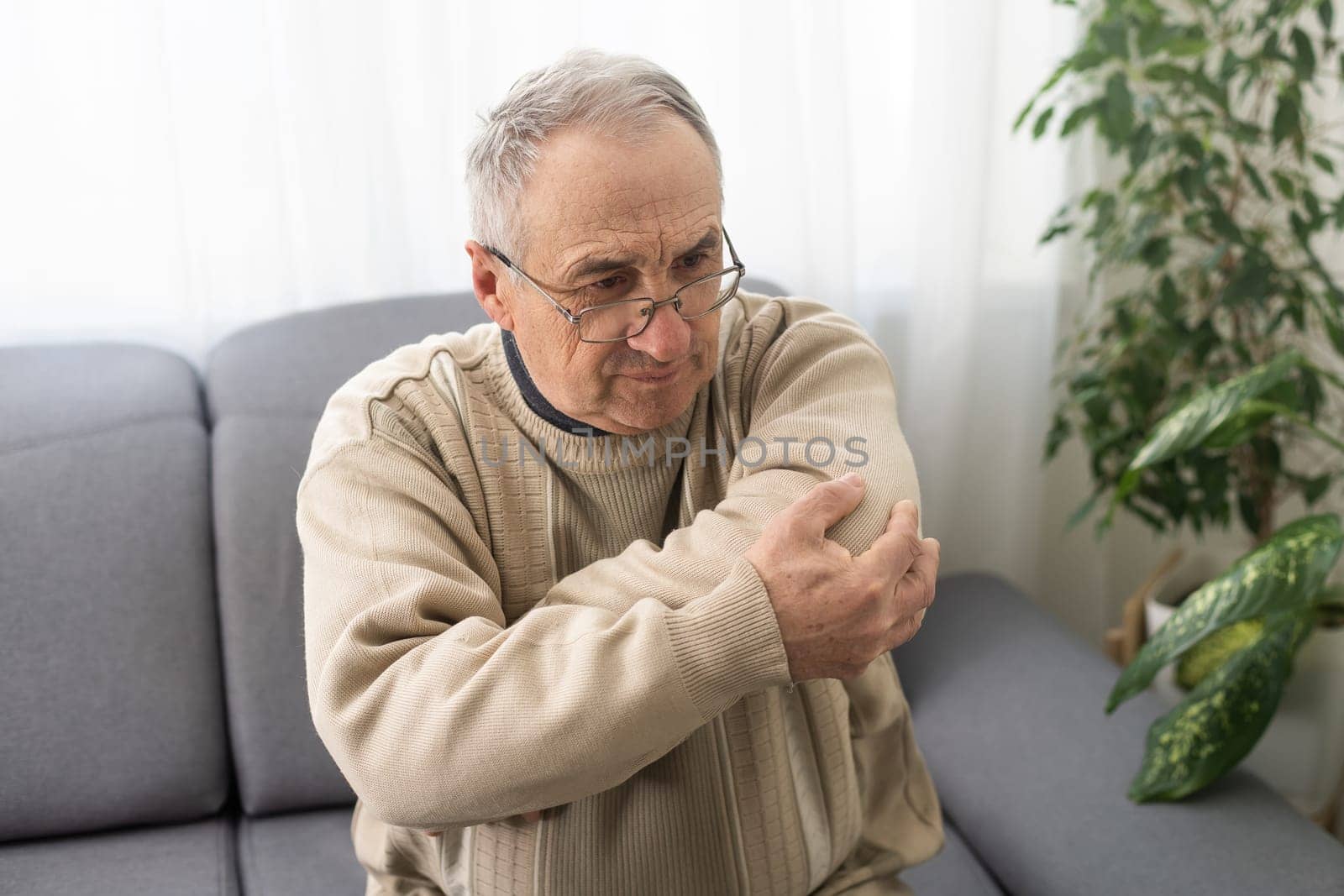 an elderly man hurts his elbow.
