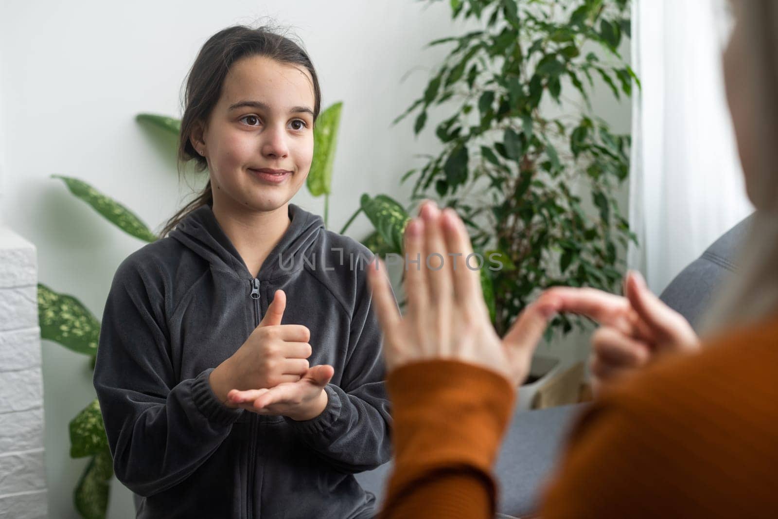 Cute little girl make hand gesture learning sign language with mom or female nanny, smiling small kid practice nonverbal talk with teacher at home, preschooler disabled child have lesson with tutor.