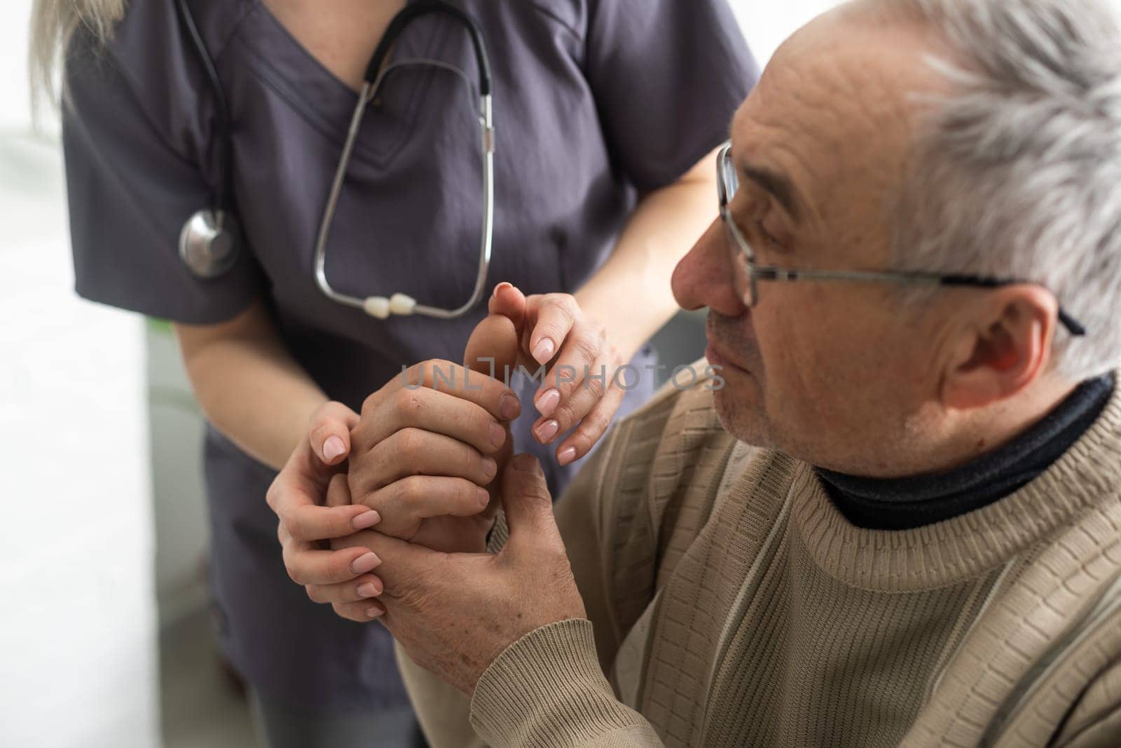 Caring nurse talks to old patient holds his hand sit in living room at homecare visit provide psychological support listen complains showing empathy encouraging. Geriatrics medicine caregiving concept.