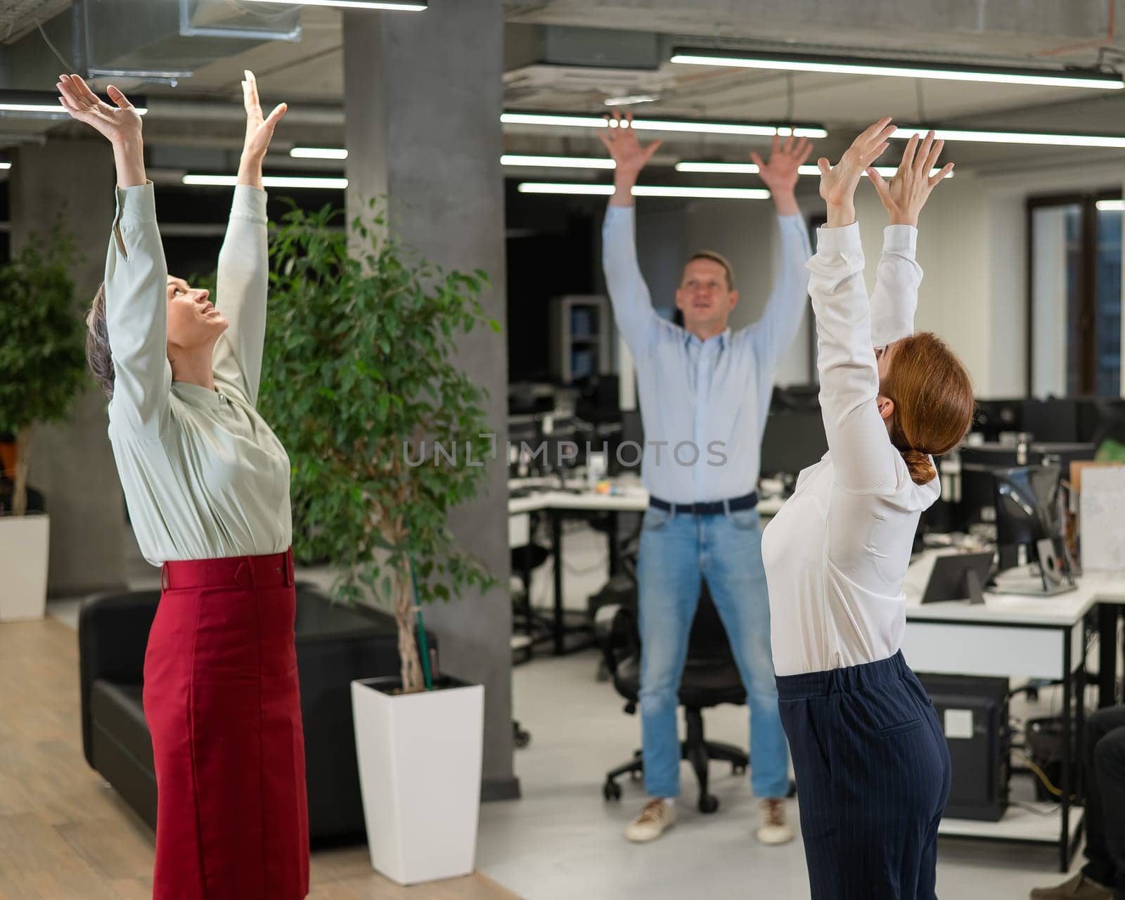 Four office workers warm up during a break. Employees do fitness exercises at the workplace