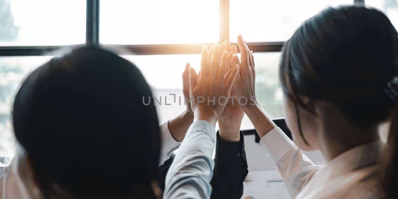 Group of business diversity workers standing with hands together high five at the office.