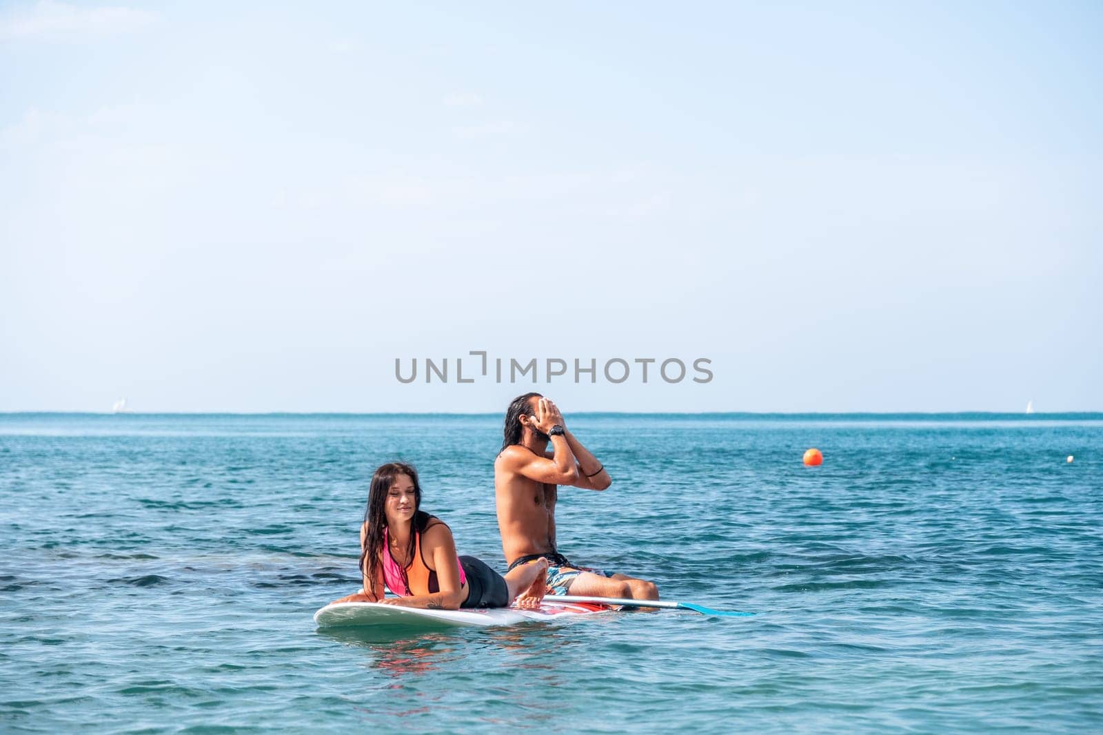 Sea woman and man on sup. Silhouette of happy young woman and man, surfing on SUP board, confident paddling through water surface. Idyllic sunset. Active lifestyle at sea or river. Slow motion by panophotograph