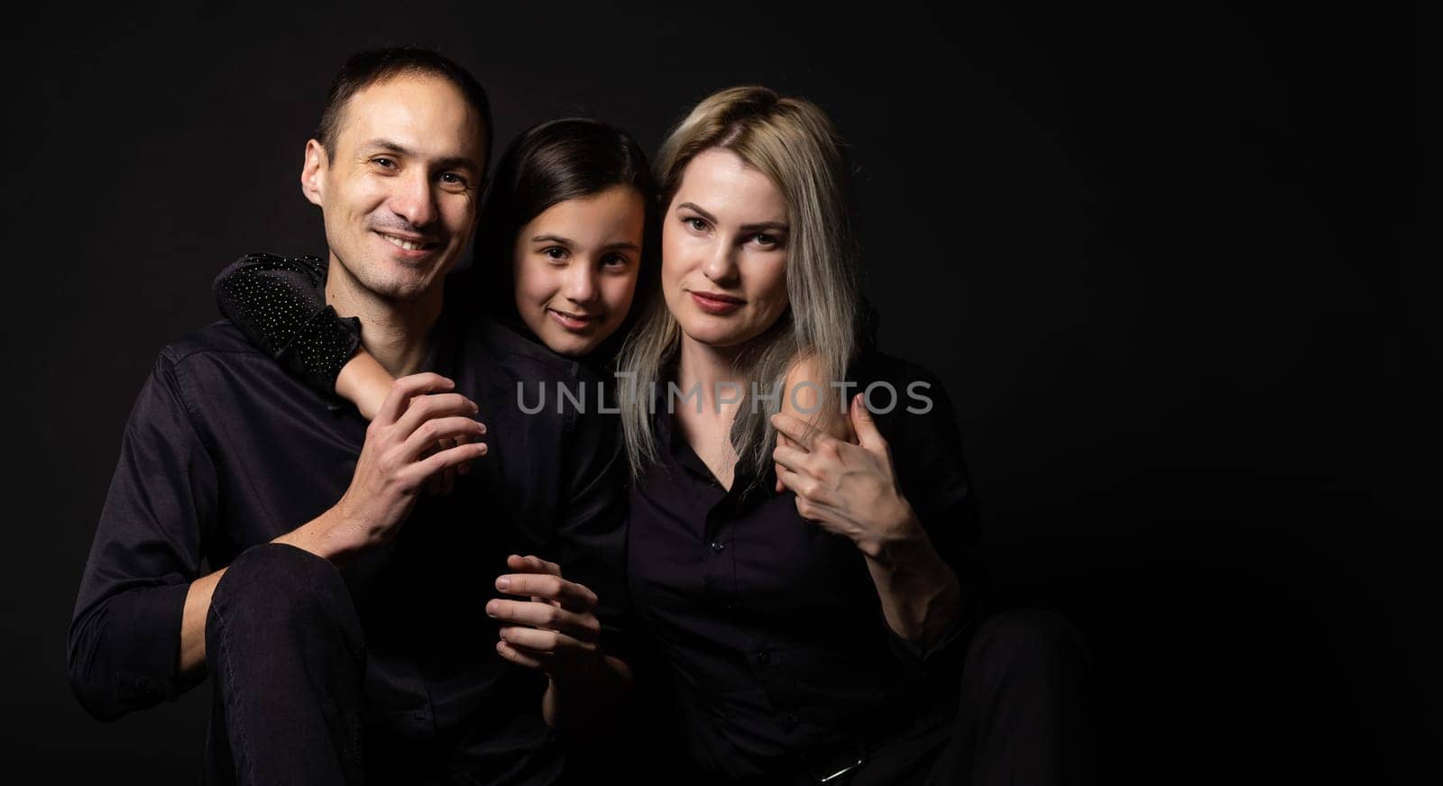Happy young family with one child having fun together isolated on black