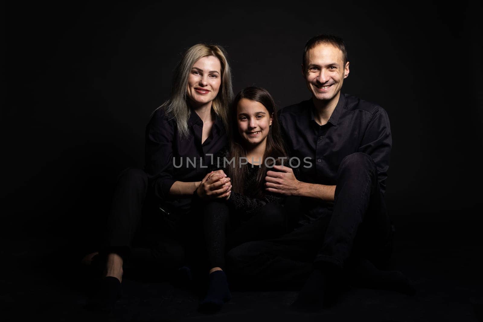 Happy young family with one child having fun together isolated on black