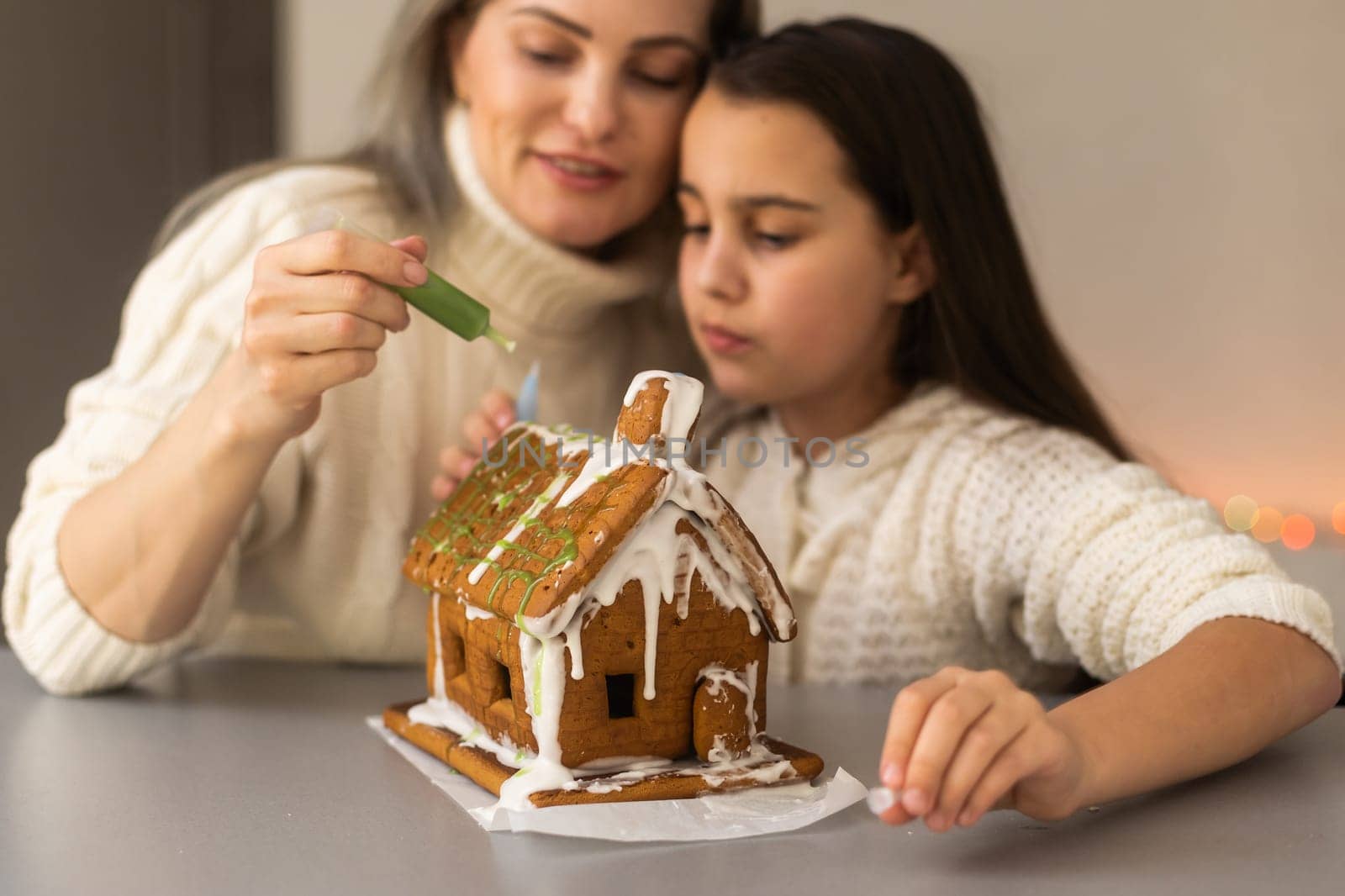 Family decorating gingerbread house on Christmas eve.