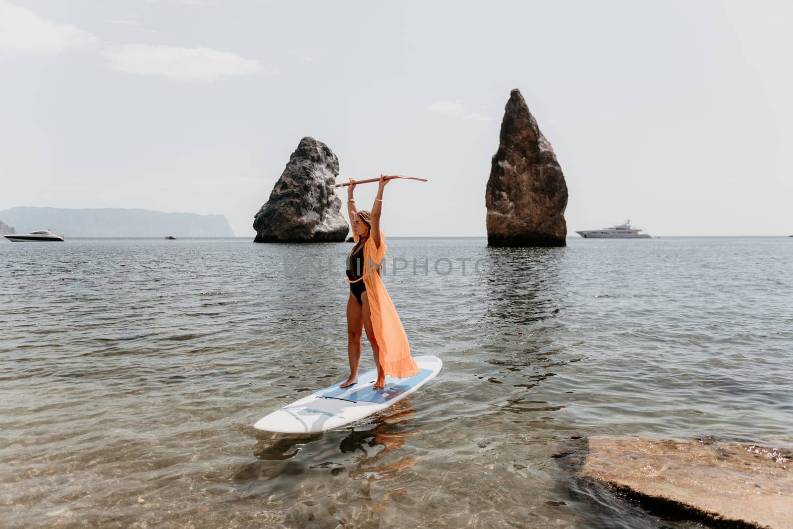 Woman sea sup. Close up portrait of happy young caucasian woman with long hair looking at camera and smiling. Cute woman portrait in bikini posing on sup board in the sea by panophotograph