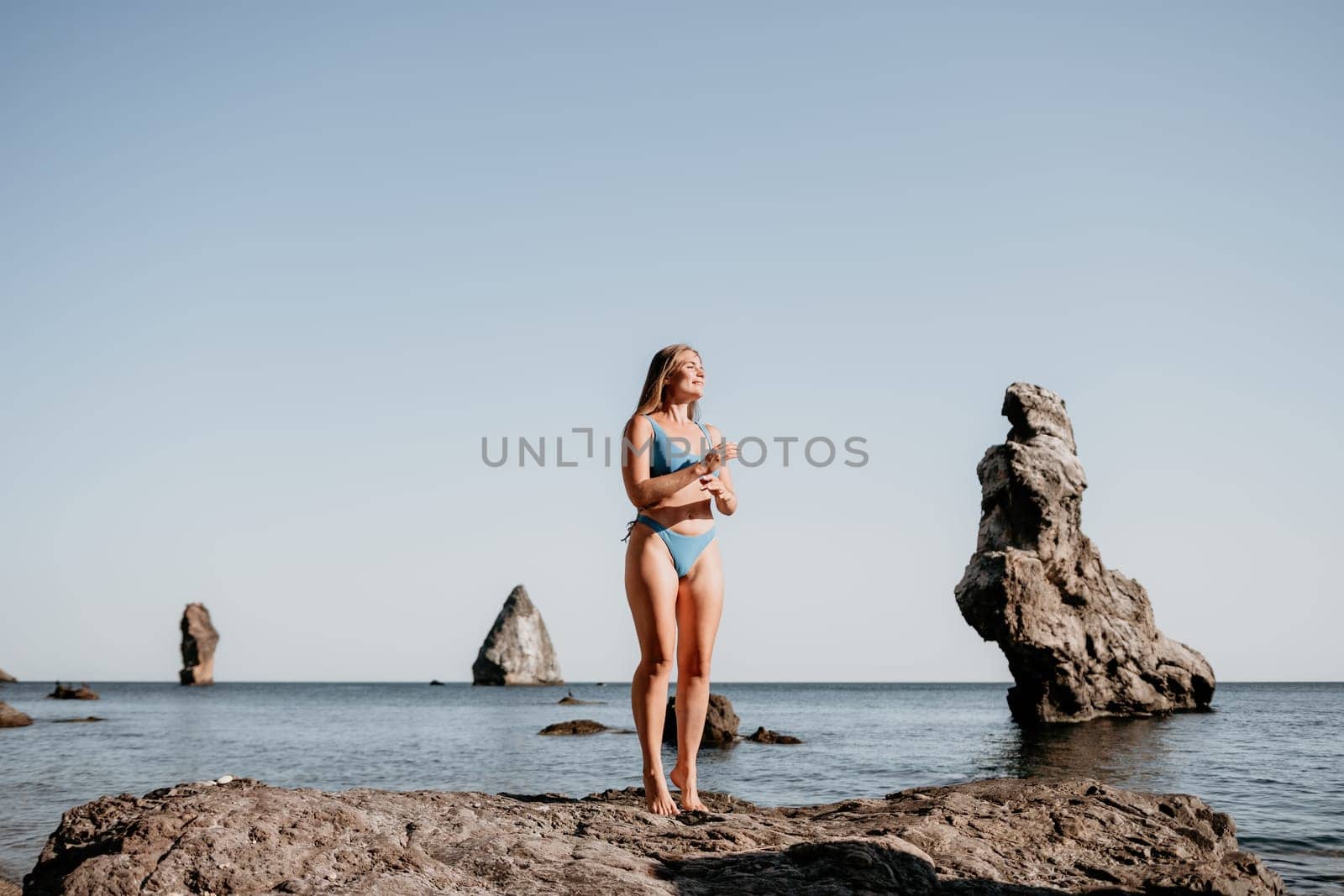 Middle aged well looking woman with black hair doing Pilates with the ring on the yoga mat near the sea on the pebble beach. Female fitness yoga concept. Healthy lifestyle, harmony and meditation.