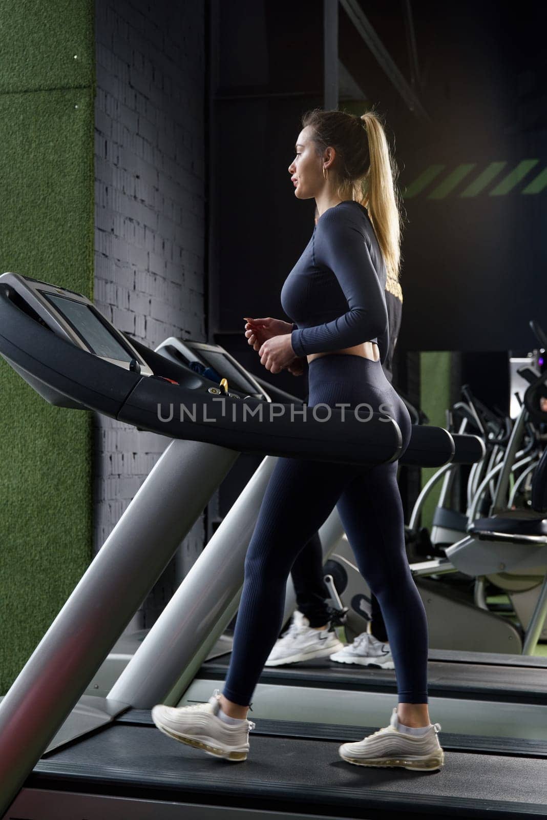 Beautiful muscular woman walking on a treadmill. wearing blue leggins and long sleeve top by Ashtray25