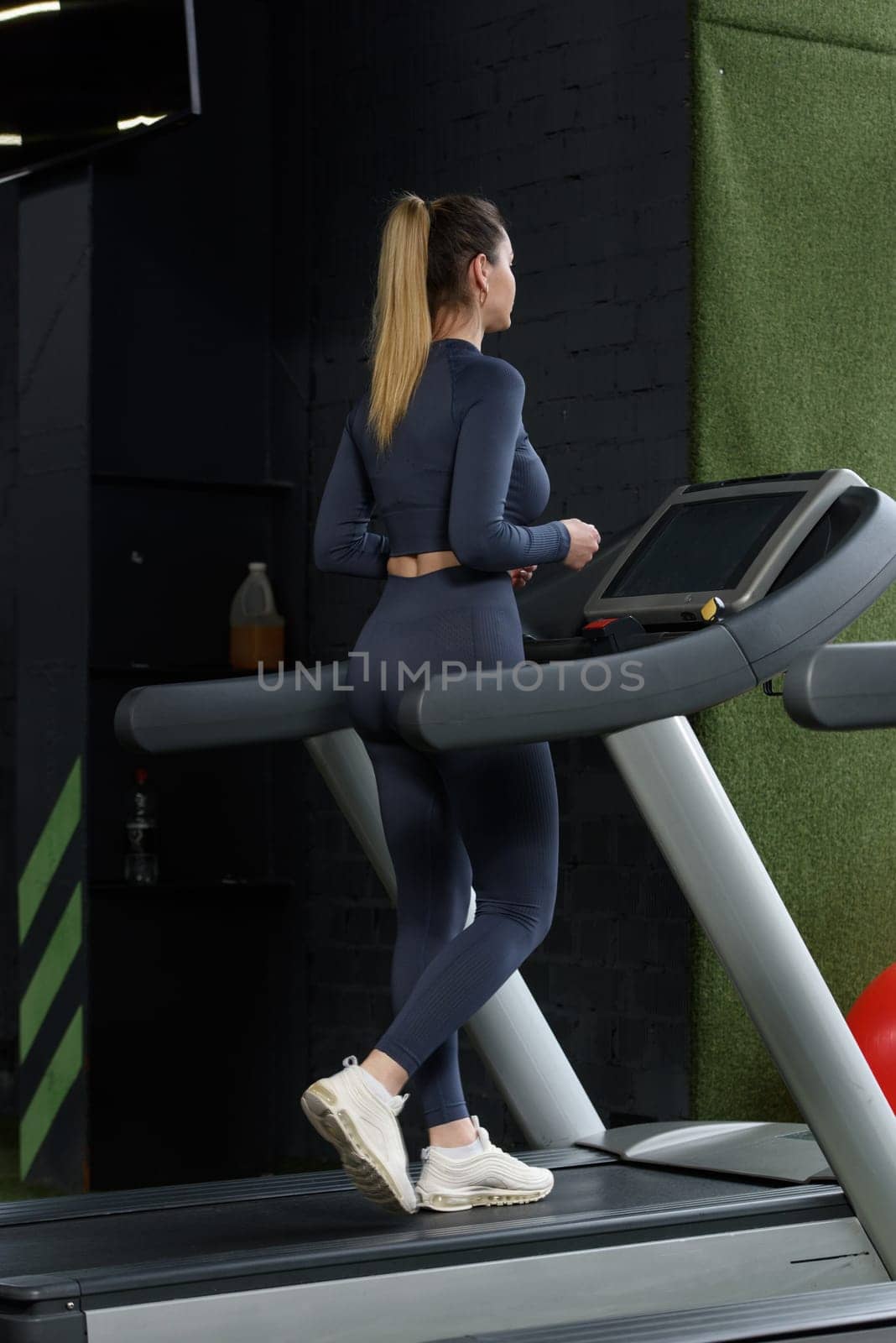 Beautiful muscular woman on a treadmill. wearing blue leggins and long sleeve top.