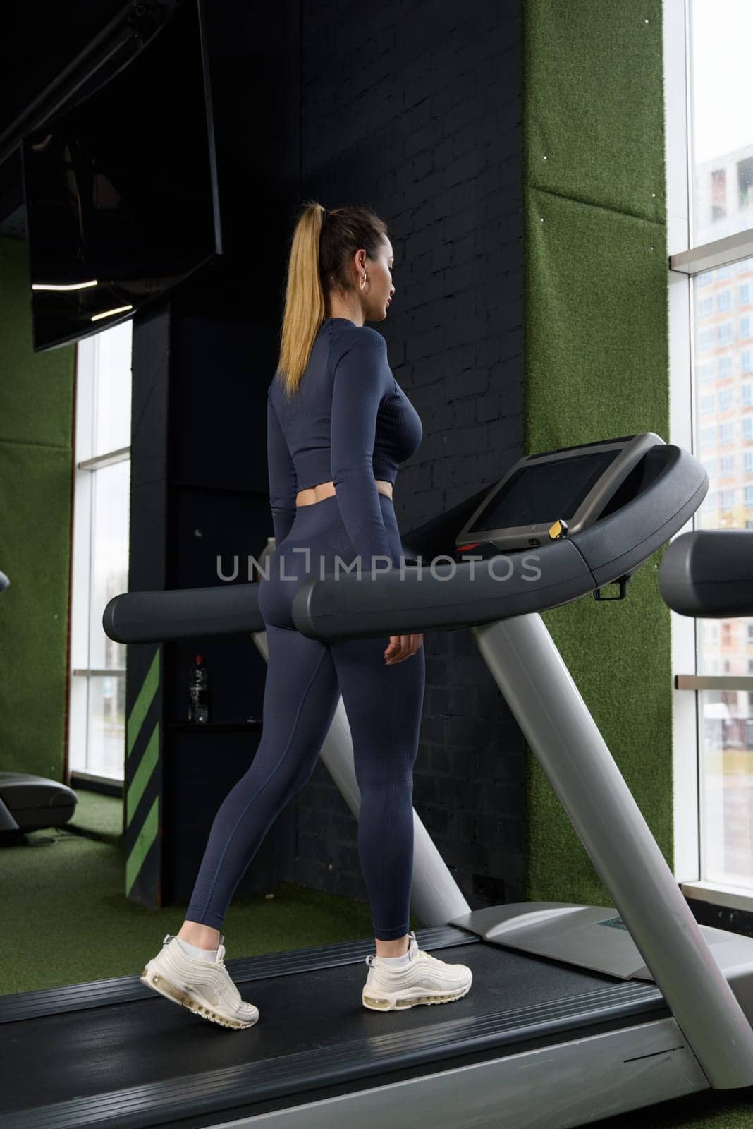 Beautiful muscular woman on a treadmill. wearing blue leggins and long sleeve top.