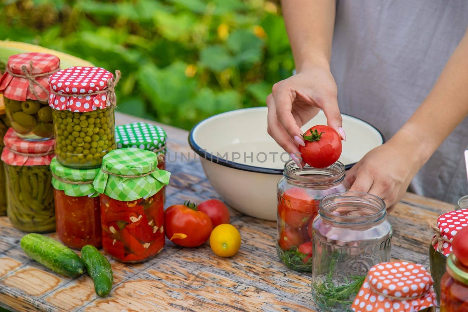 A woman preserves vegetables in jars. Selective focus. Food.
