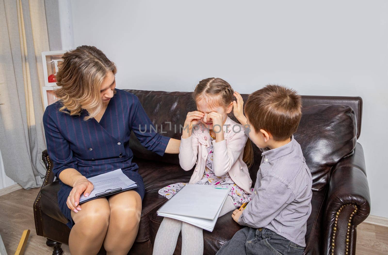 Girl psychologist calms upset girl. The kid is crying