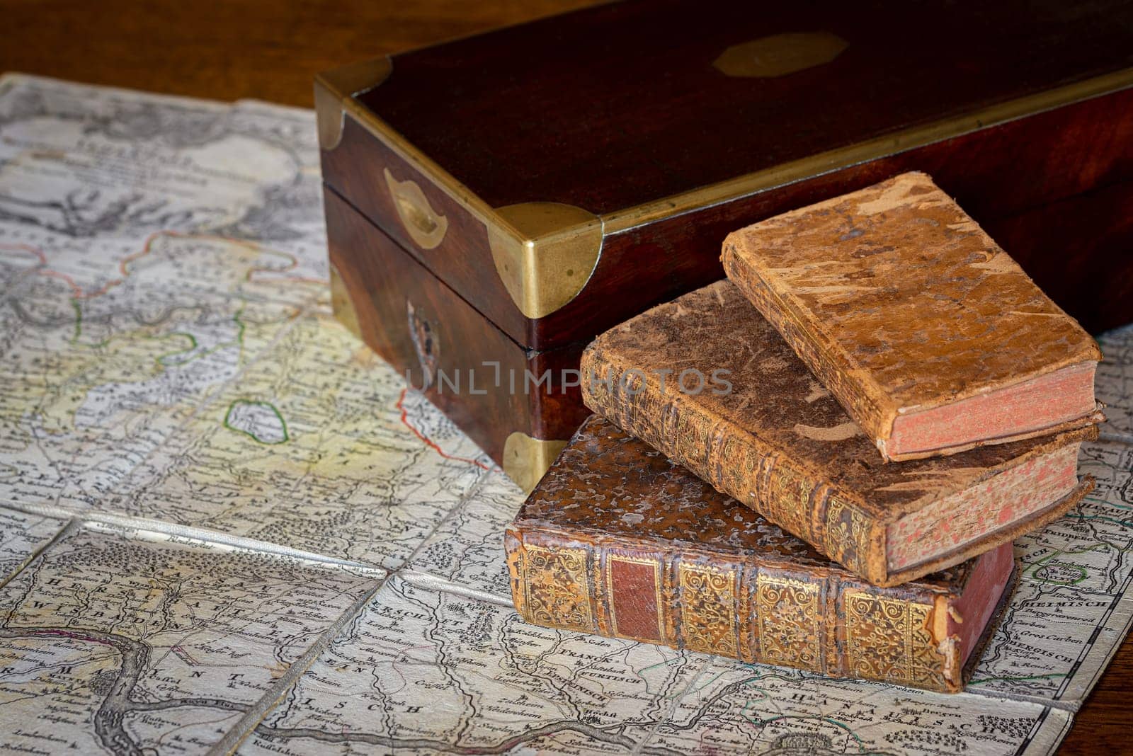 Pile of antique books and a box on an ancient map by MaxalTamor