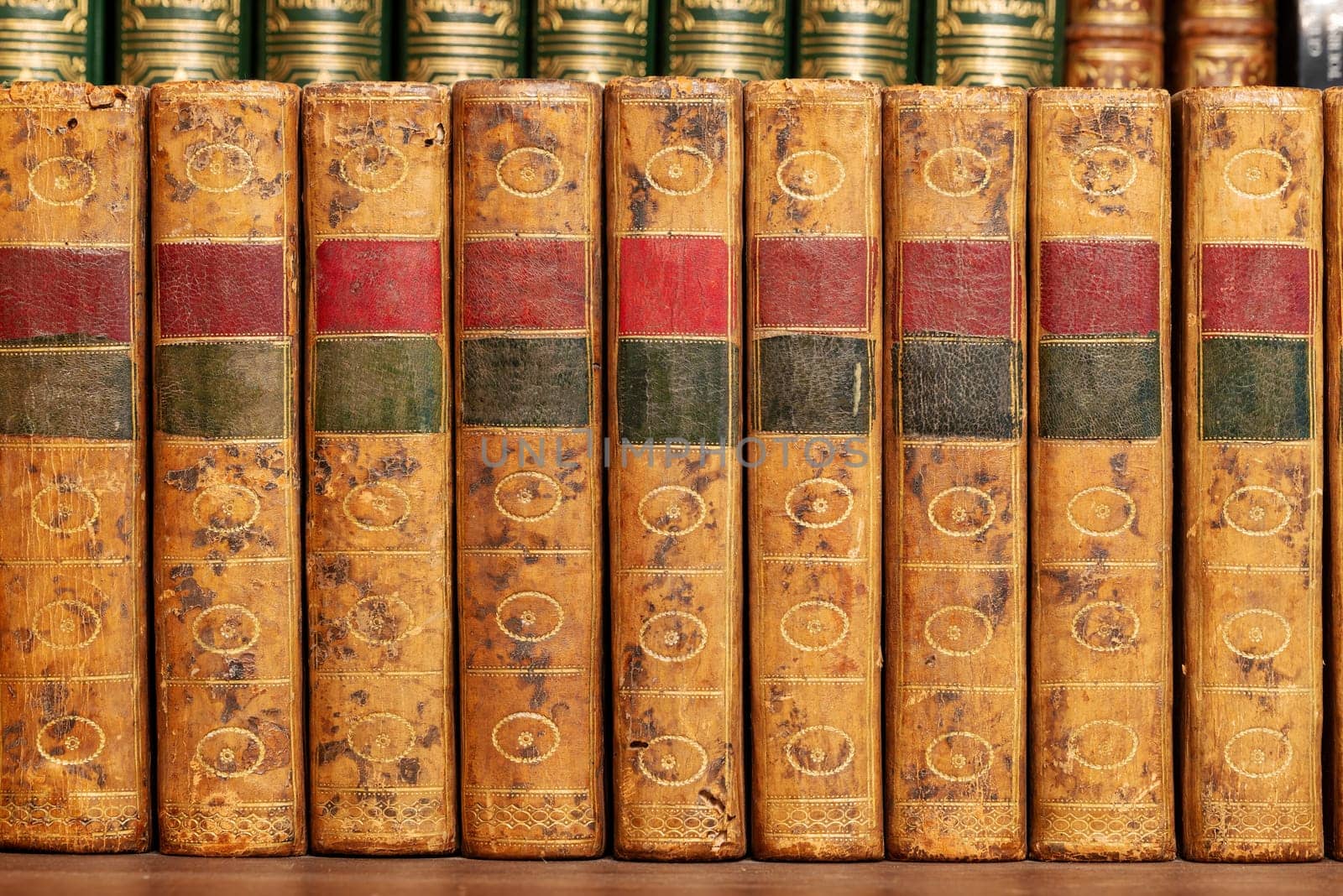 Pile of antique books with a leather cover and golden ornaments on a wooden table