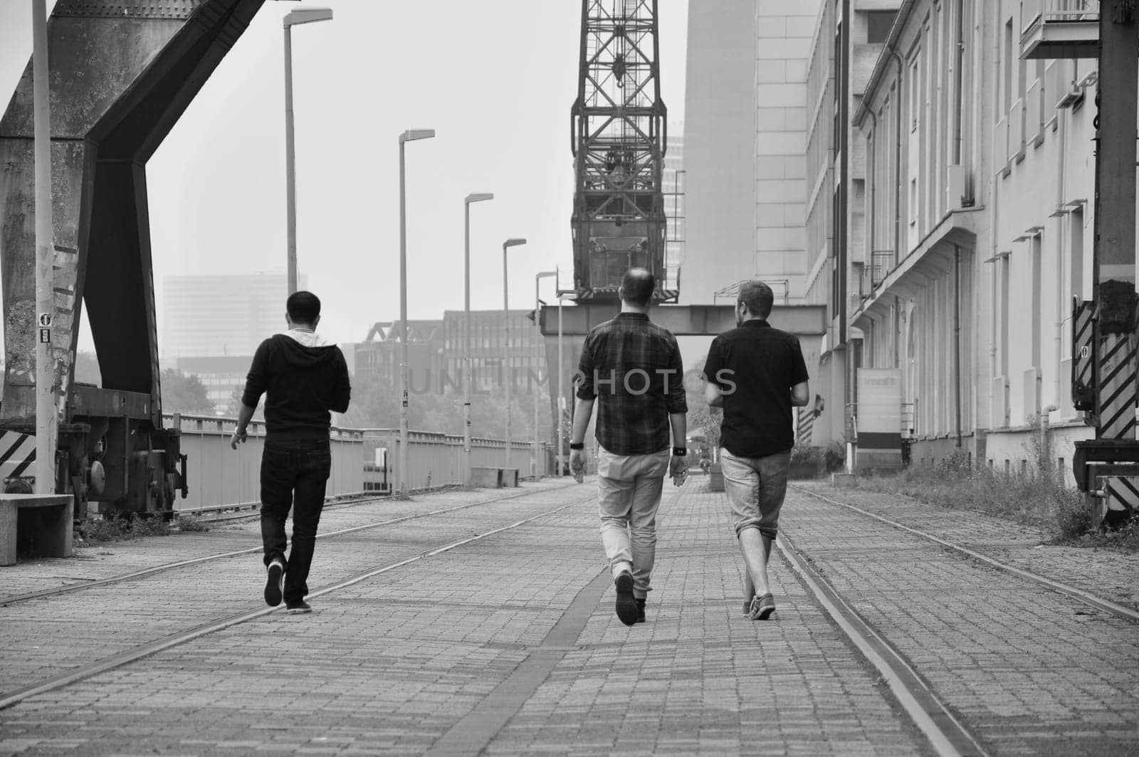 Grayscale shot of three men walking on the quay of the Media Harbor in Dusseldorf, Germany.