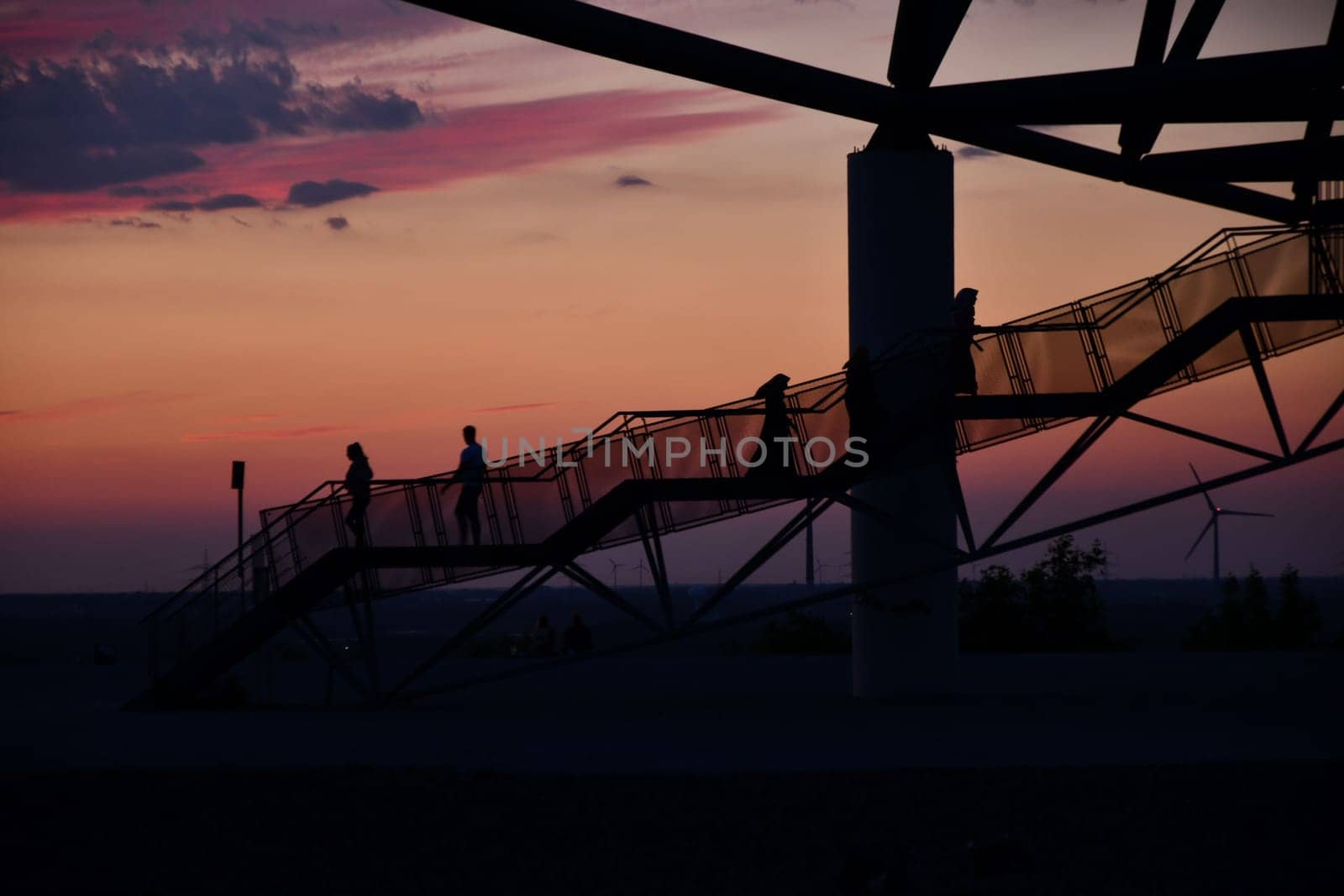 Silhouettes of people of the viewing platform Tetraeder Bottrop in Bottrop, Germany at sunset